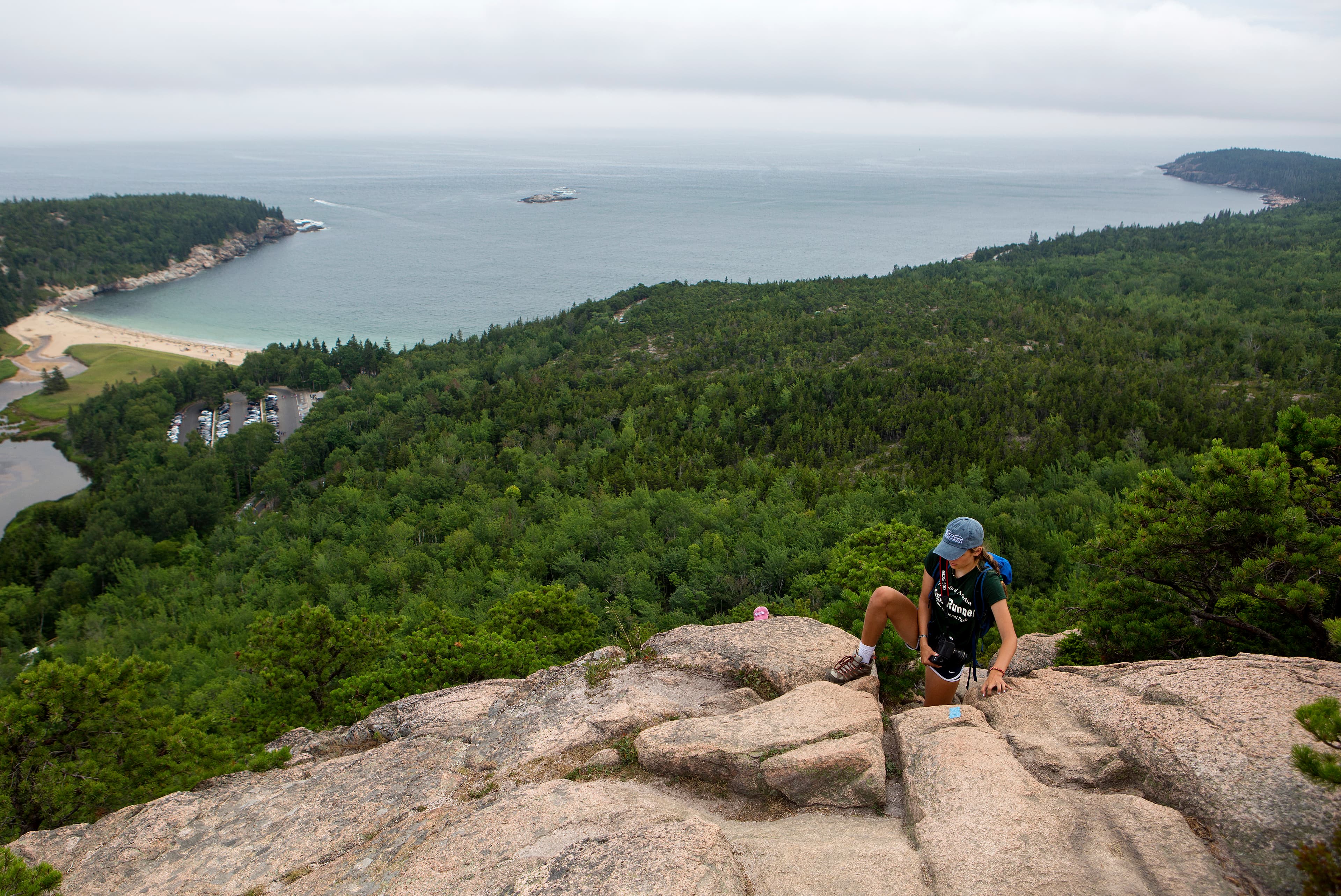 person climbing up rocks with a ocean view in the distance