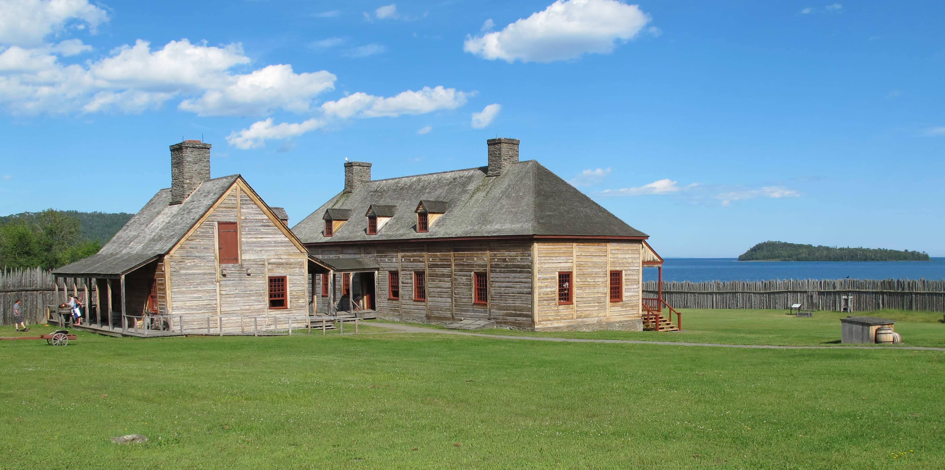 Reconstructed historic wood buildings on a lawn.