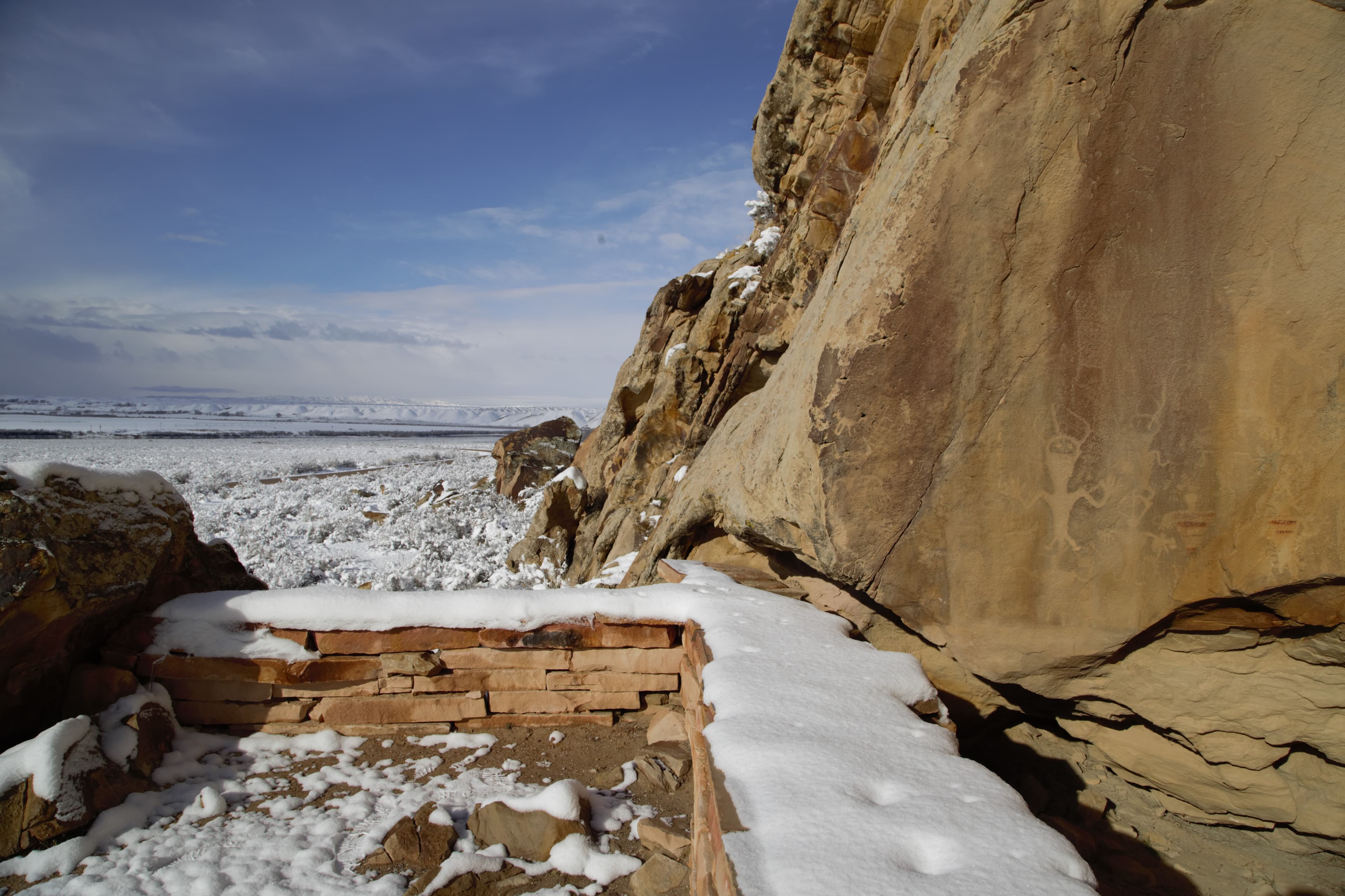 A short stone wall covered in snow offers a place to view petroglyphs and pictographs.