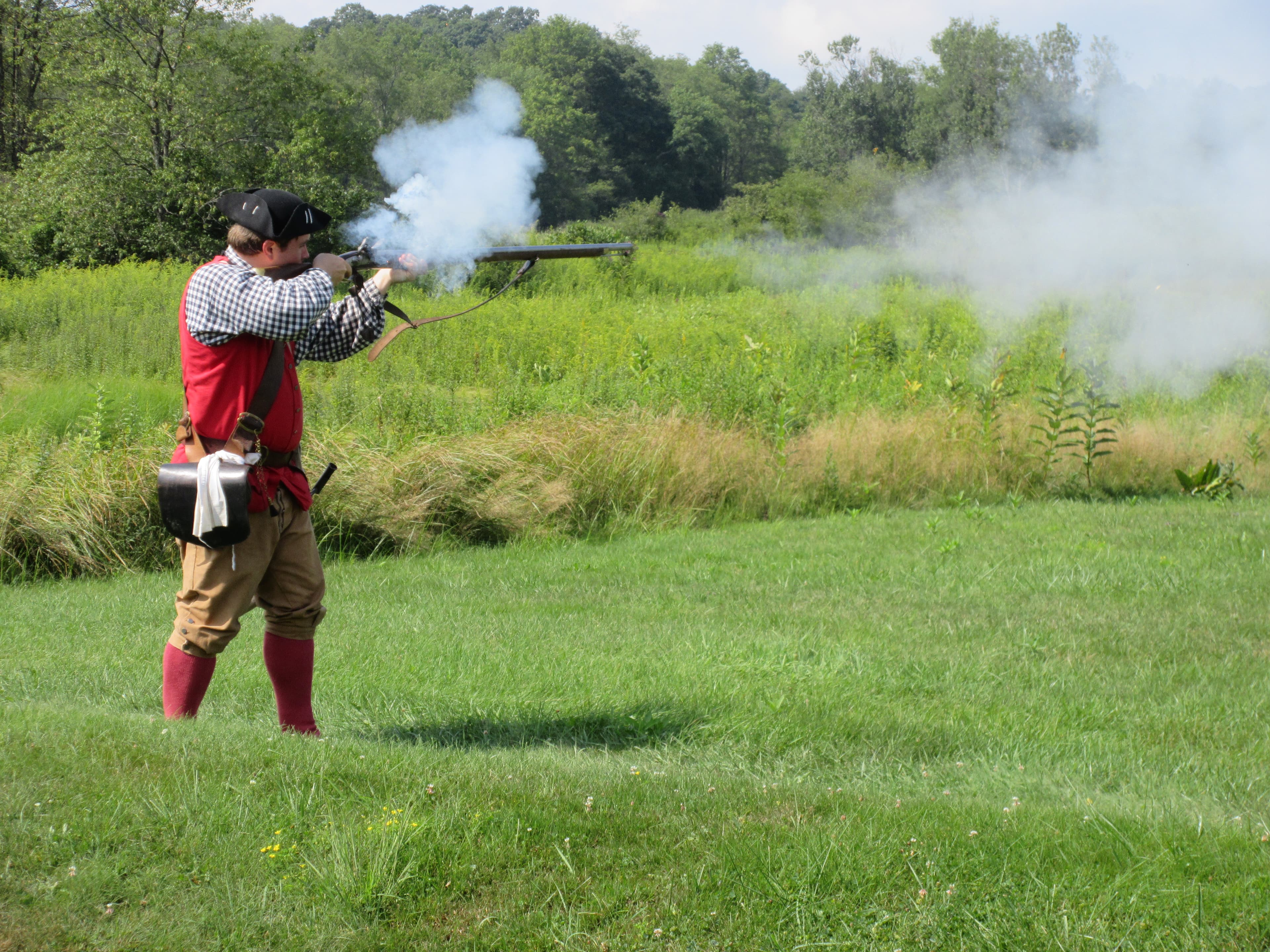 Demonstrator in period clothing firing a flintlock musket.