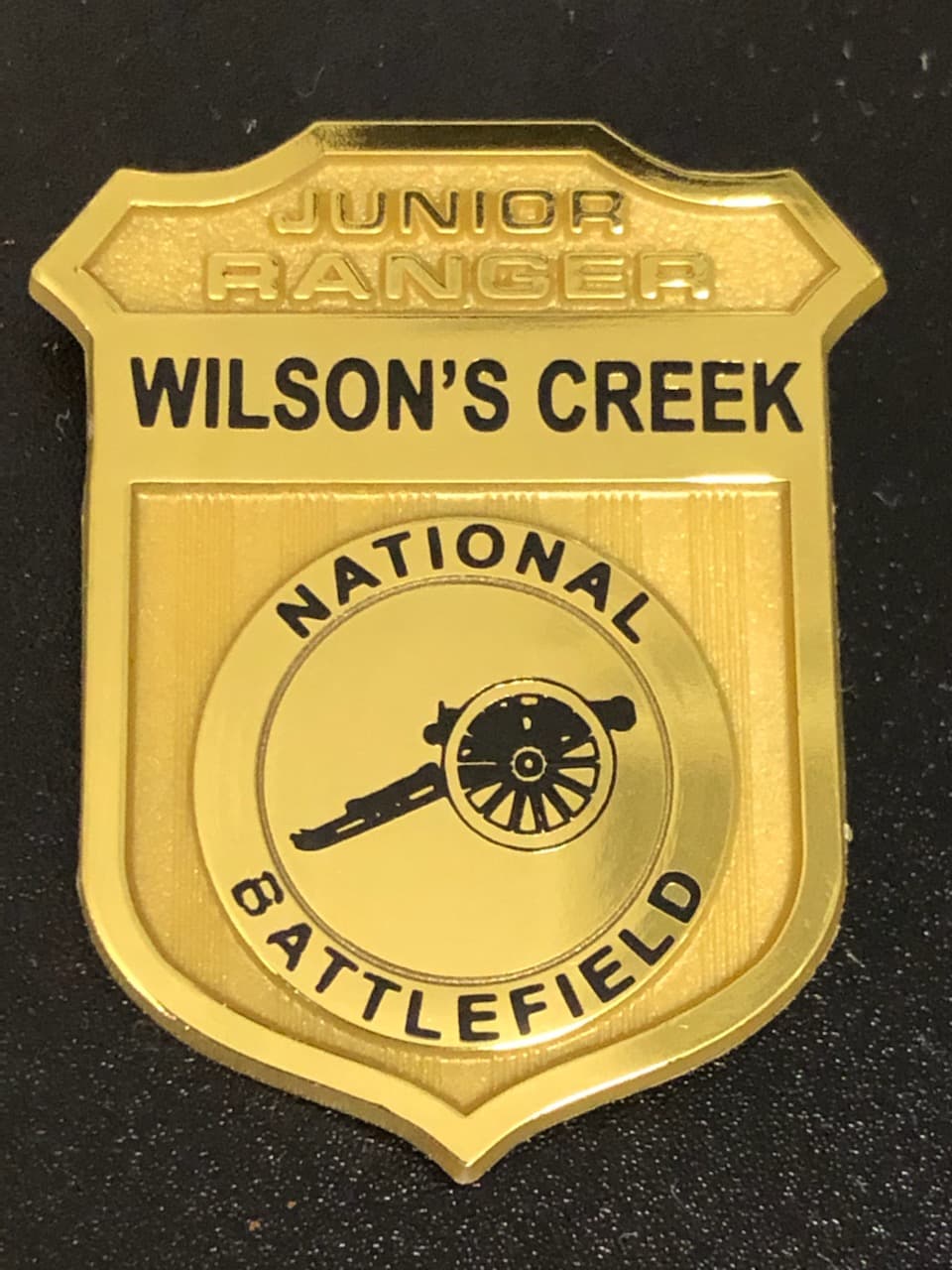 Plastic Junior Ranger badge with Wilson's Creek National Battlefield on it and a cannon emblem