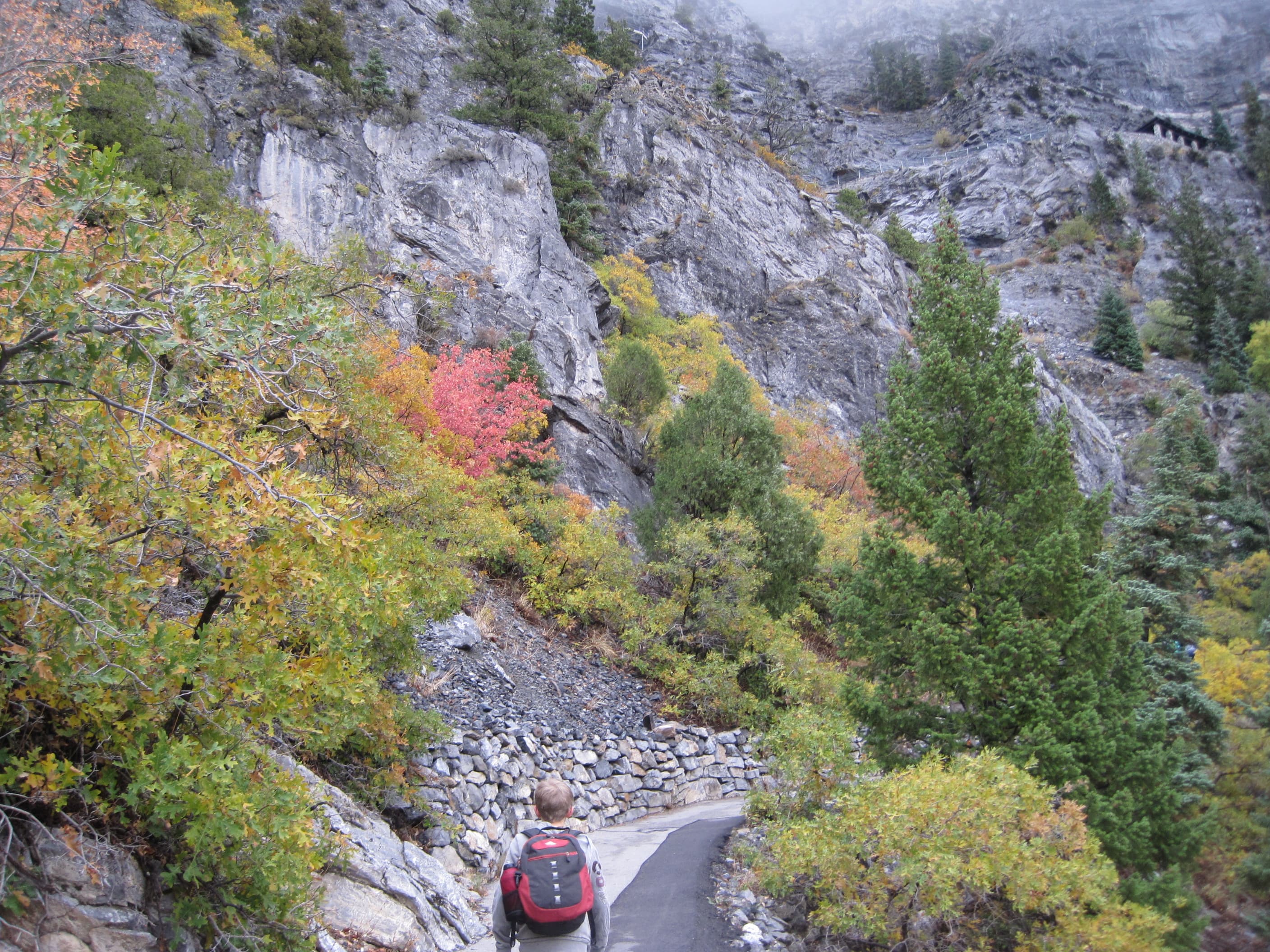 Young boy walking up trail with backpack and jacket