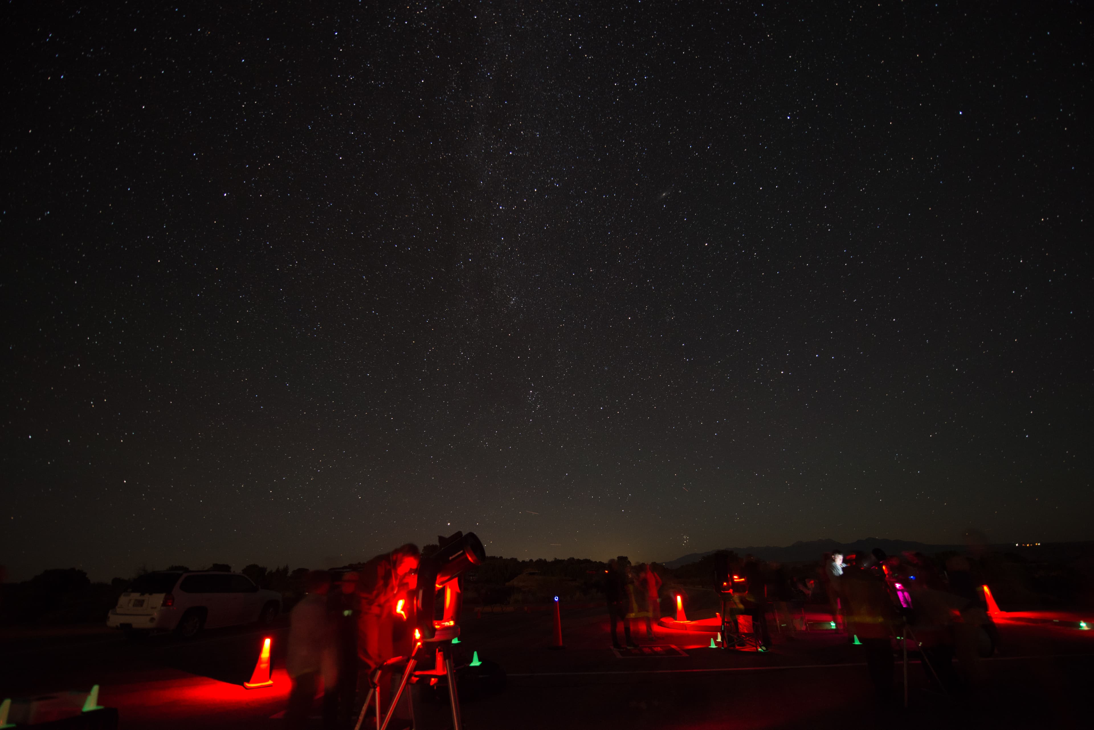 telescopes illuminated red beneath a star-filled sky