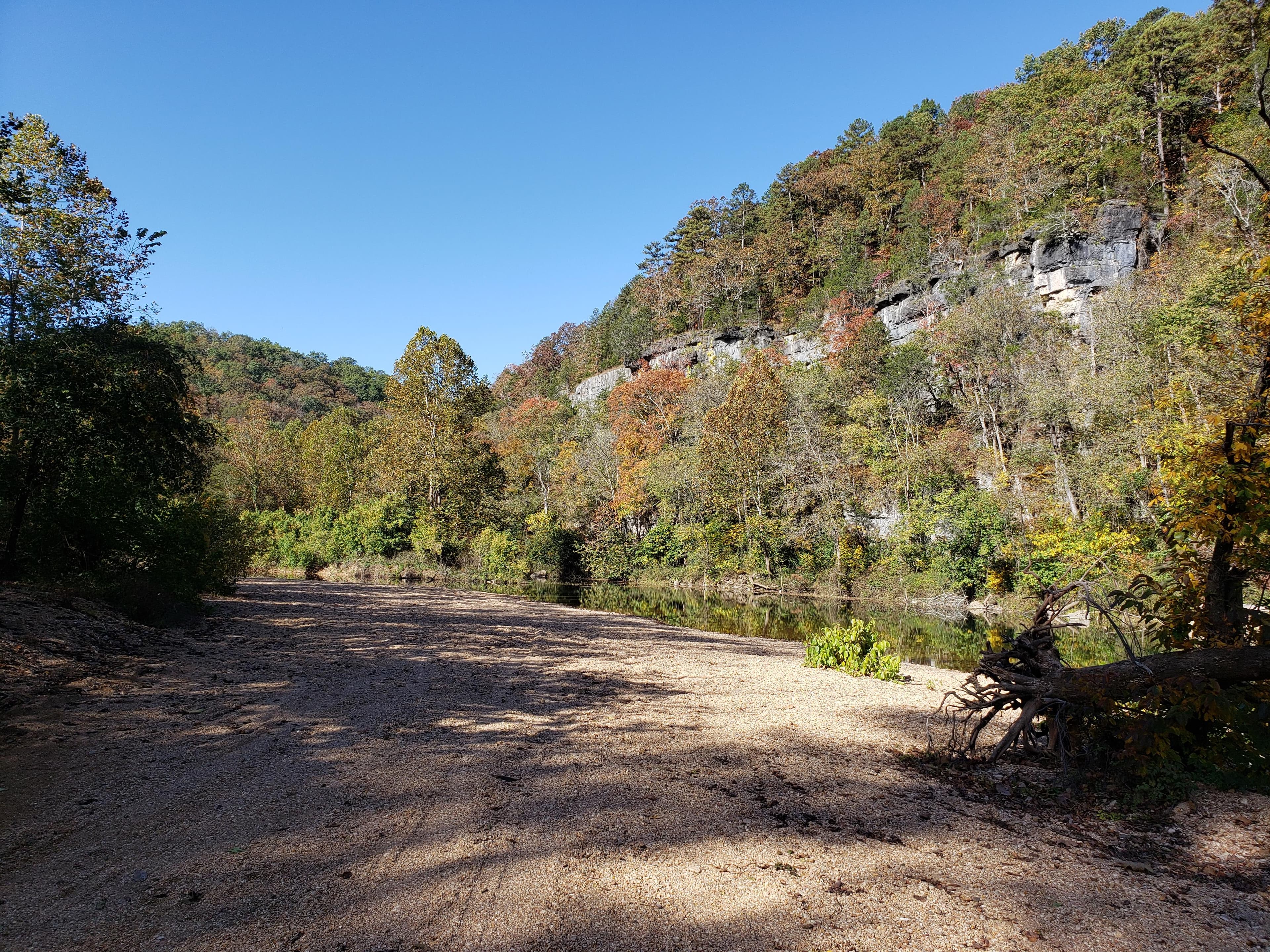 A large bluff lines a shallow river.
