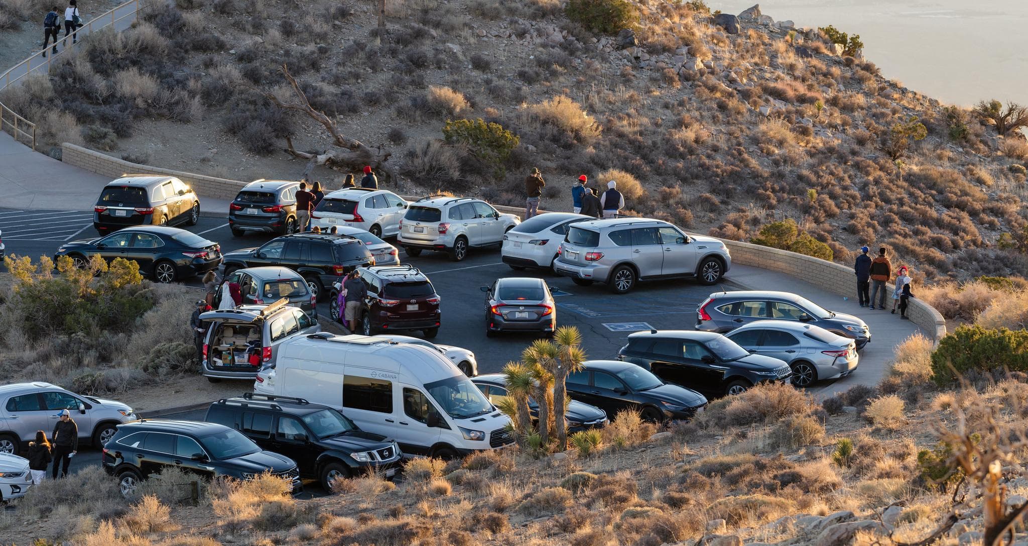 Vehicles and people in a paved parking area