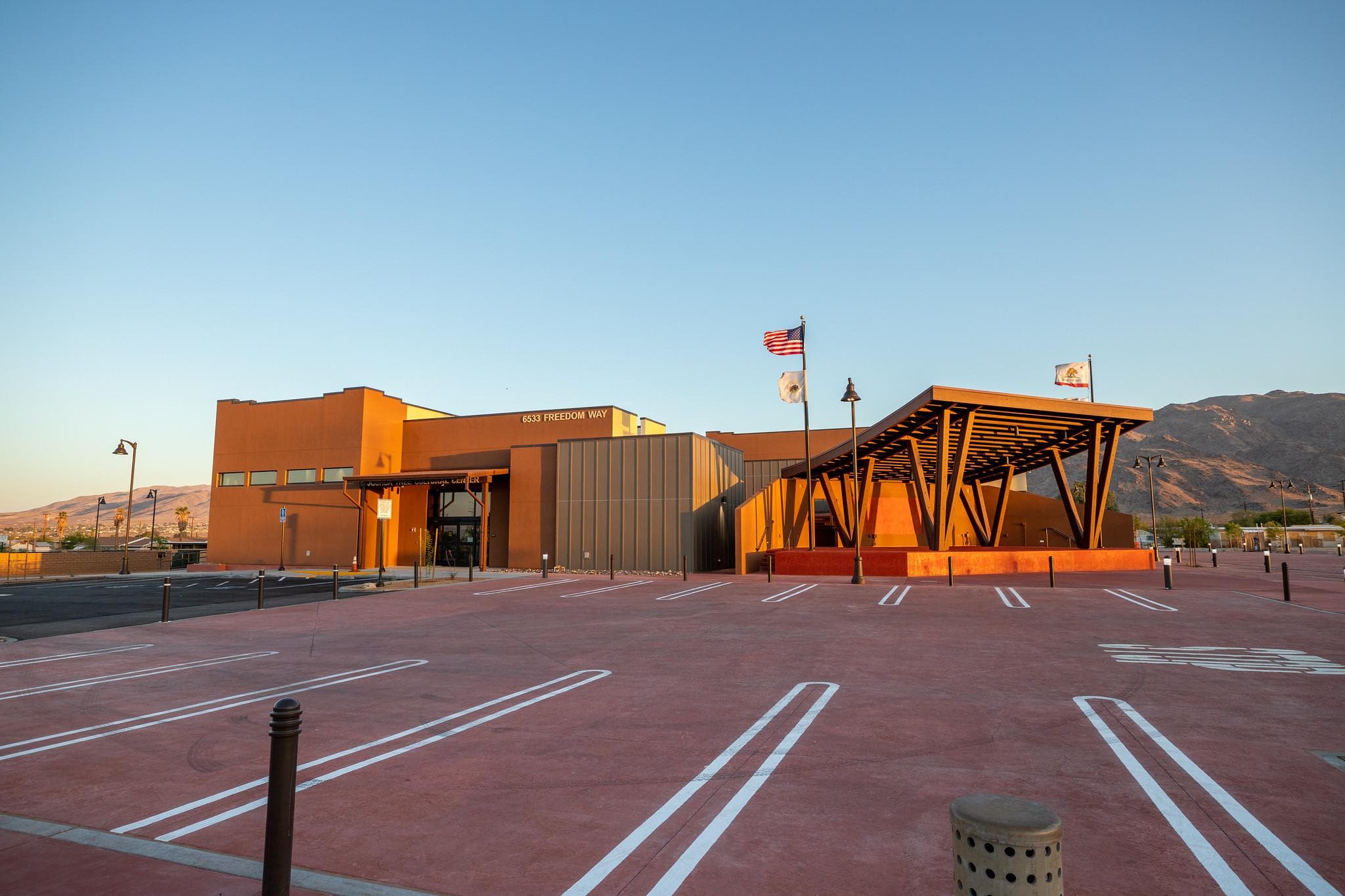 Parking spaces and s building with a sign that reads Joshua Tree Cultural Center
