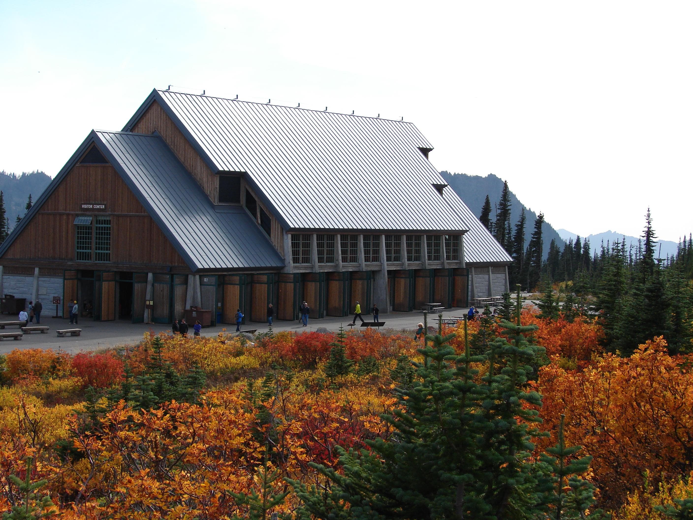 A large building sits surrounded by the bright reds, oranges and yellows of fall.
