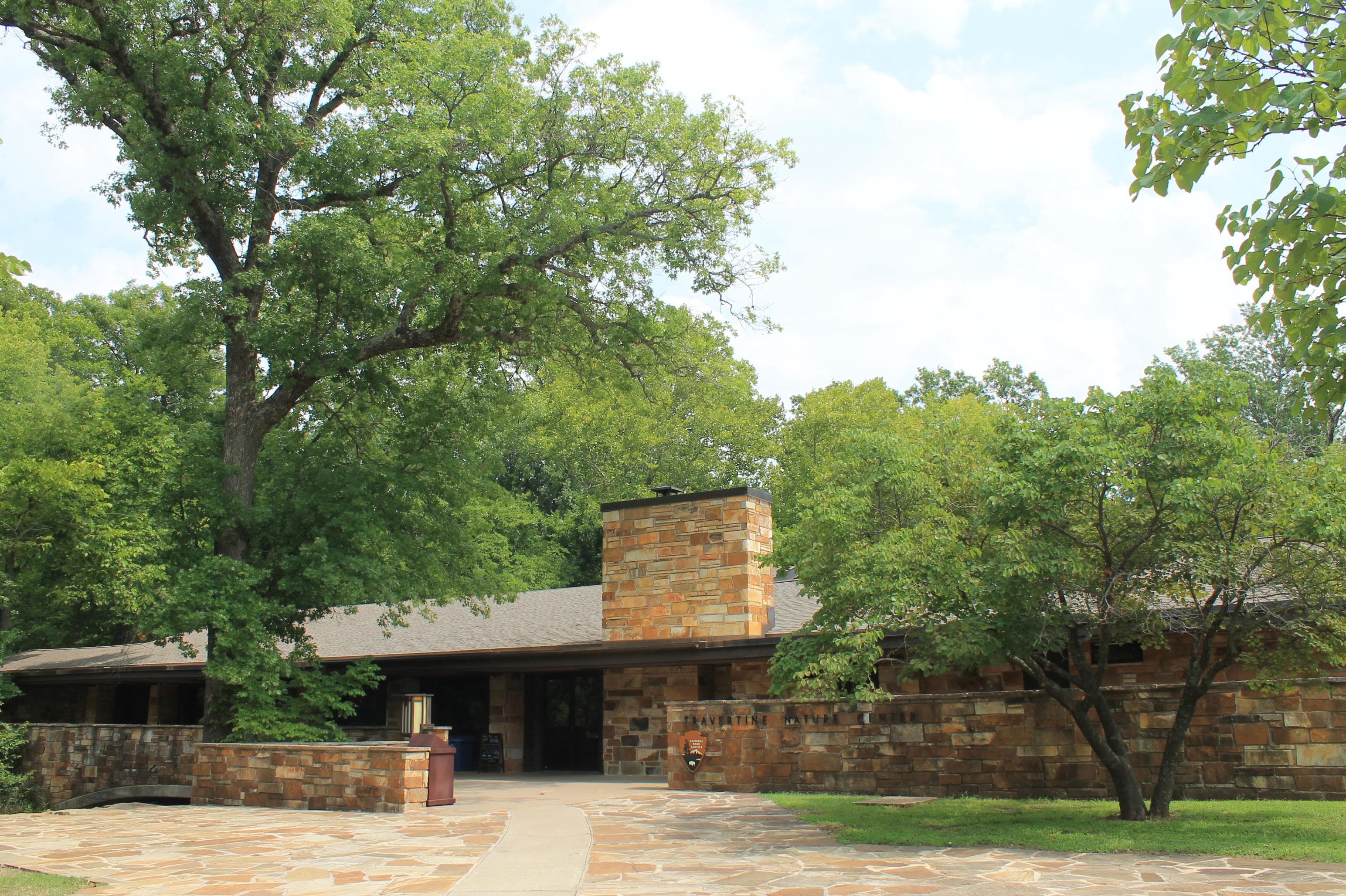 A low, wide building made of stone surrounded by trees.