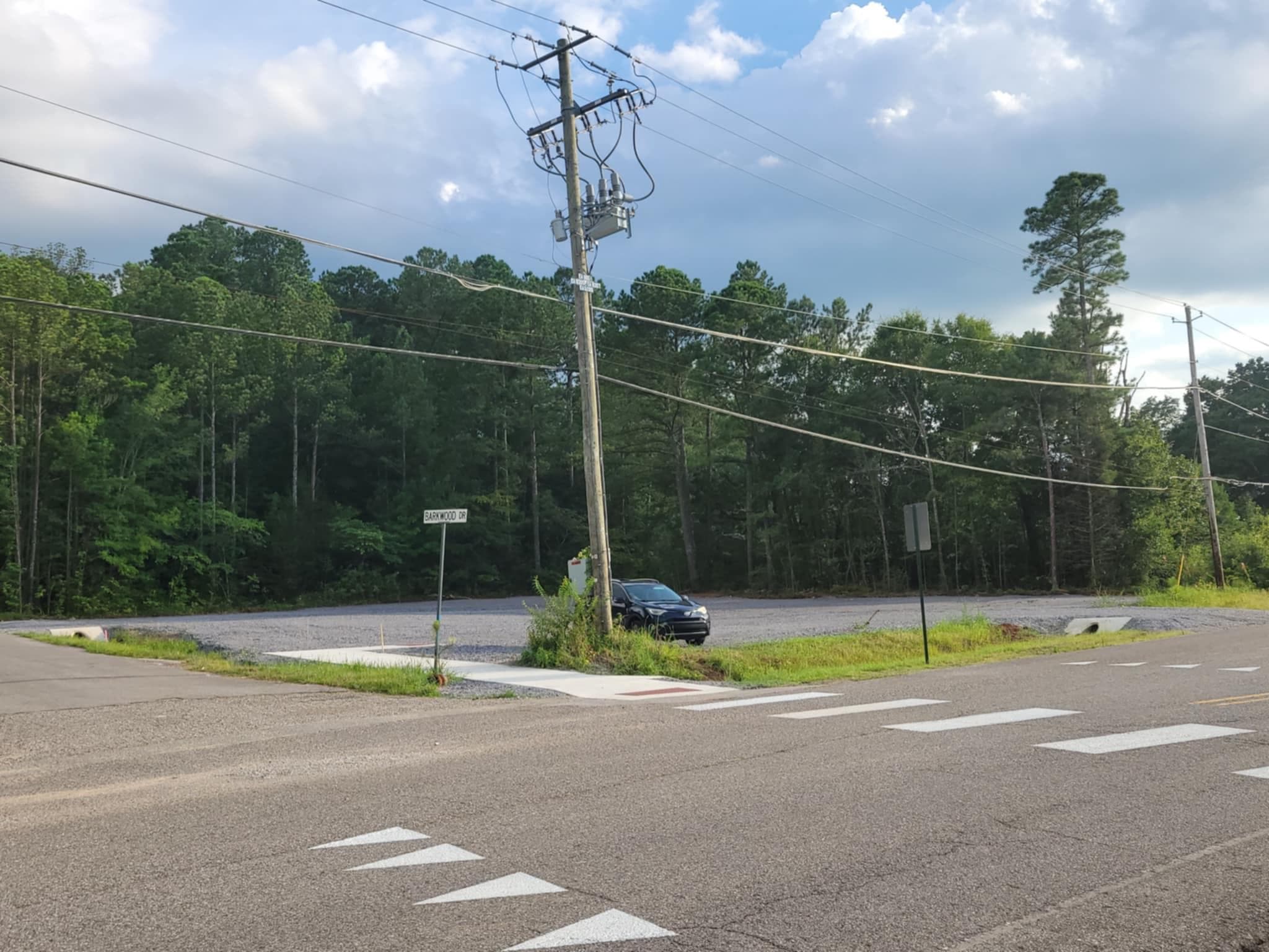 A gravel parking lot sitting on the corner of Old Birmngham Highway and Barkwood Drive.