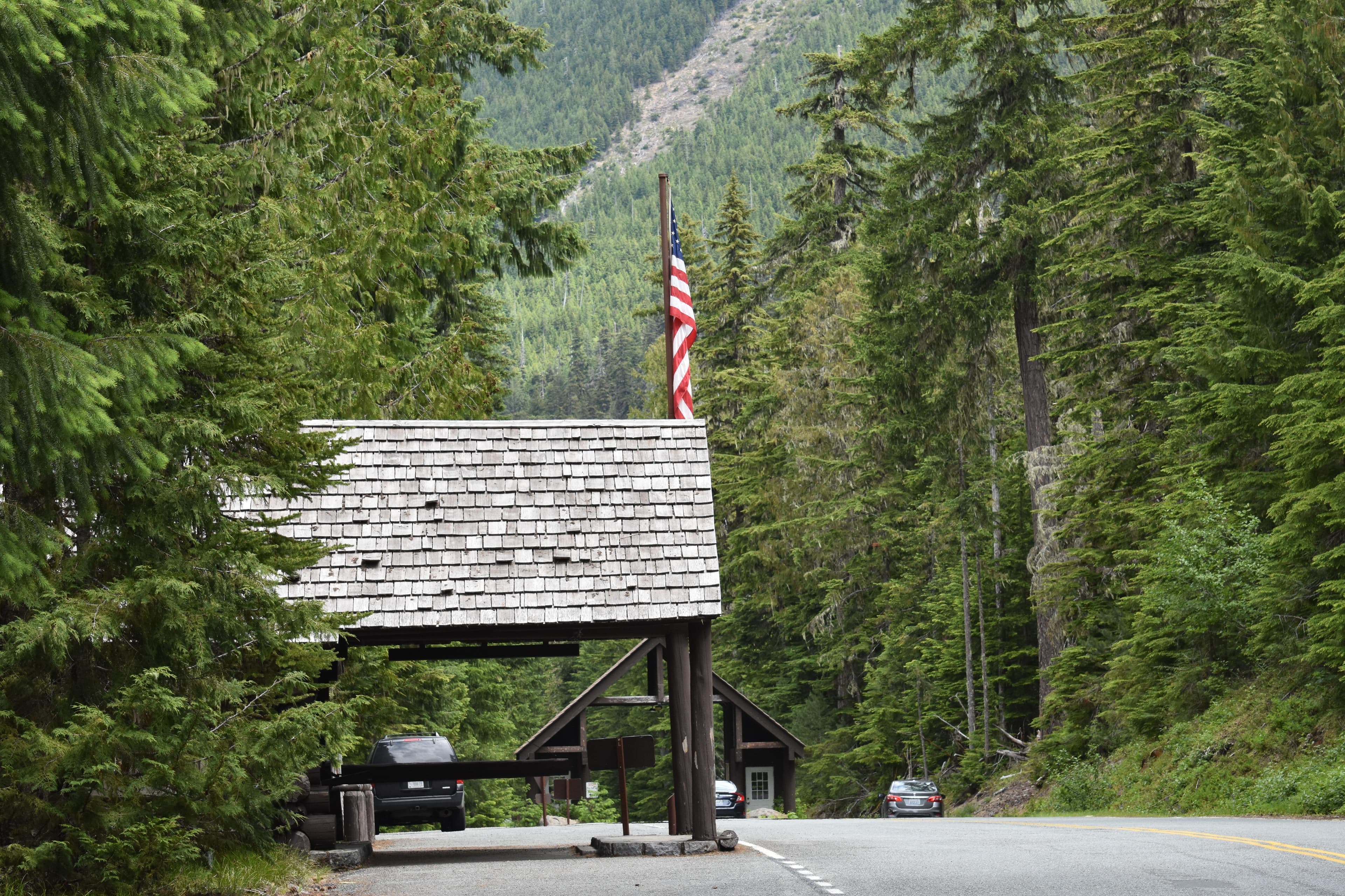 The shingled porch of a rustic building with an entrance in the background.