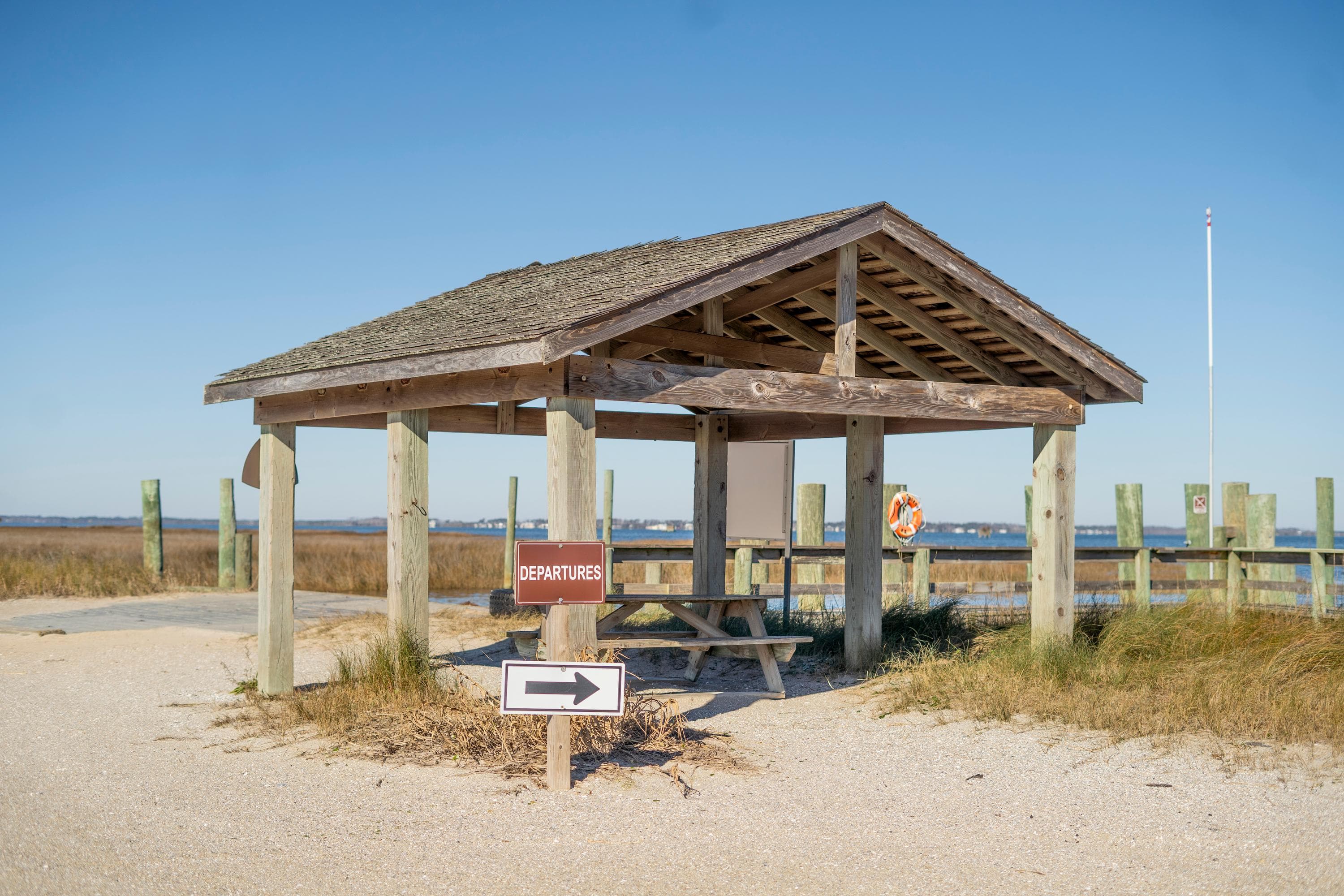 A wood pavilion with an arrow pointing right. Dock in the background