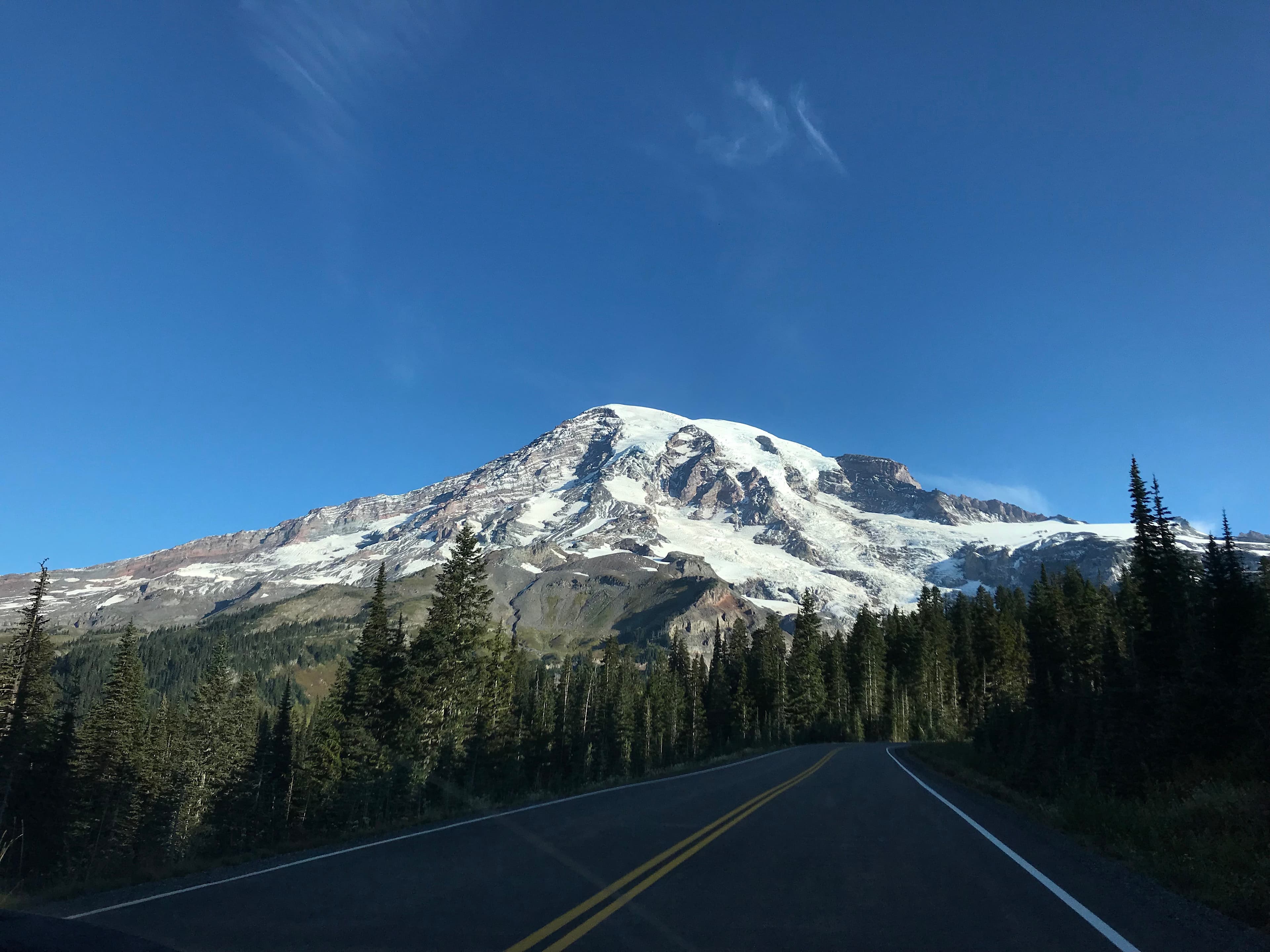 A road leads towards a glaciated mountain peak.