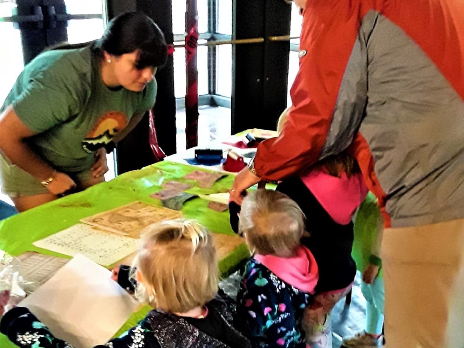 A woman helping 2 little girls and their dad with an activity