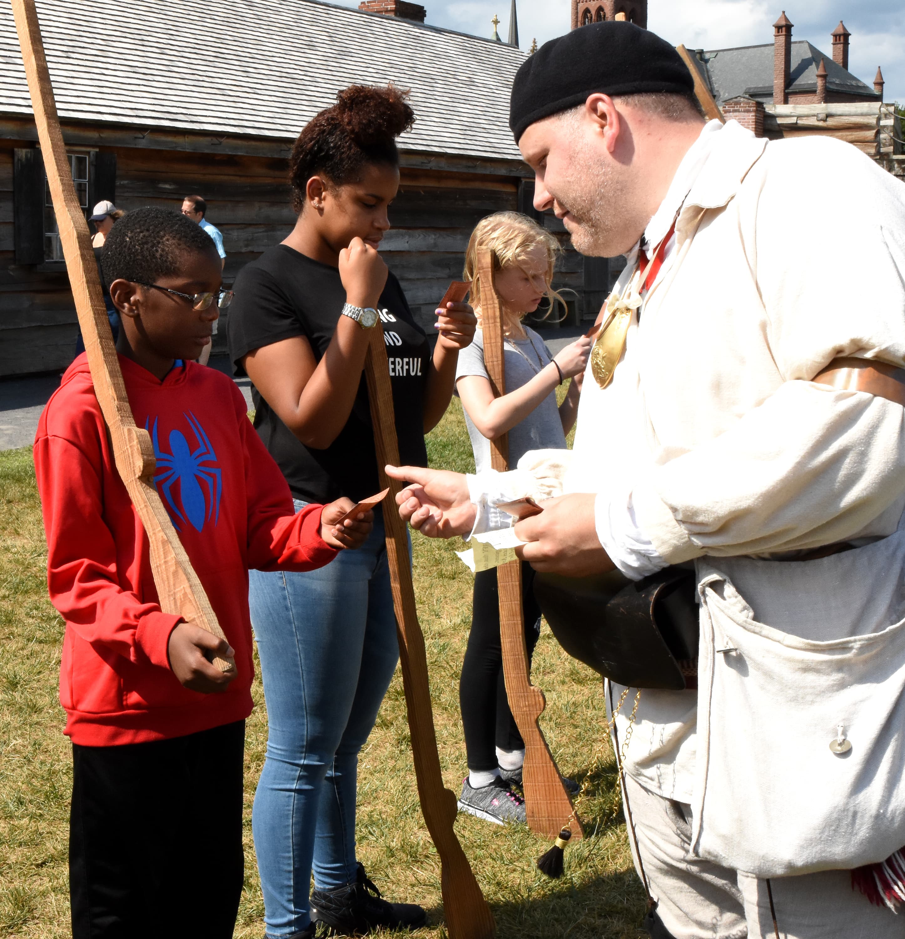 A boy stands opposite from a Continental Soldier, holding a wooden musket