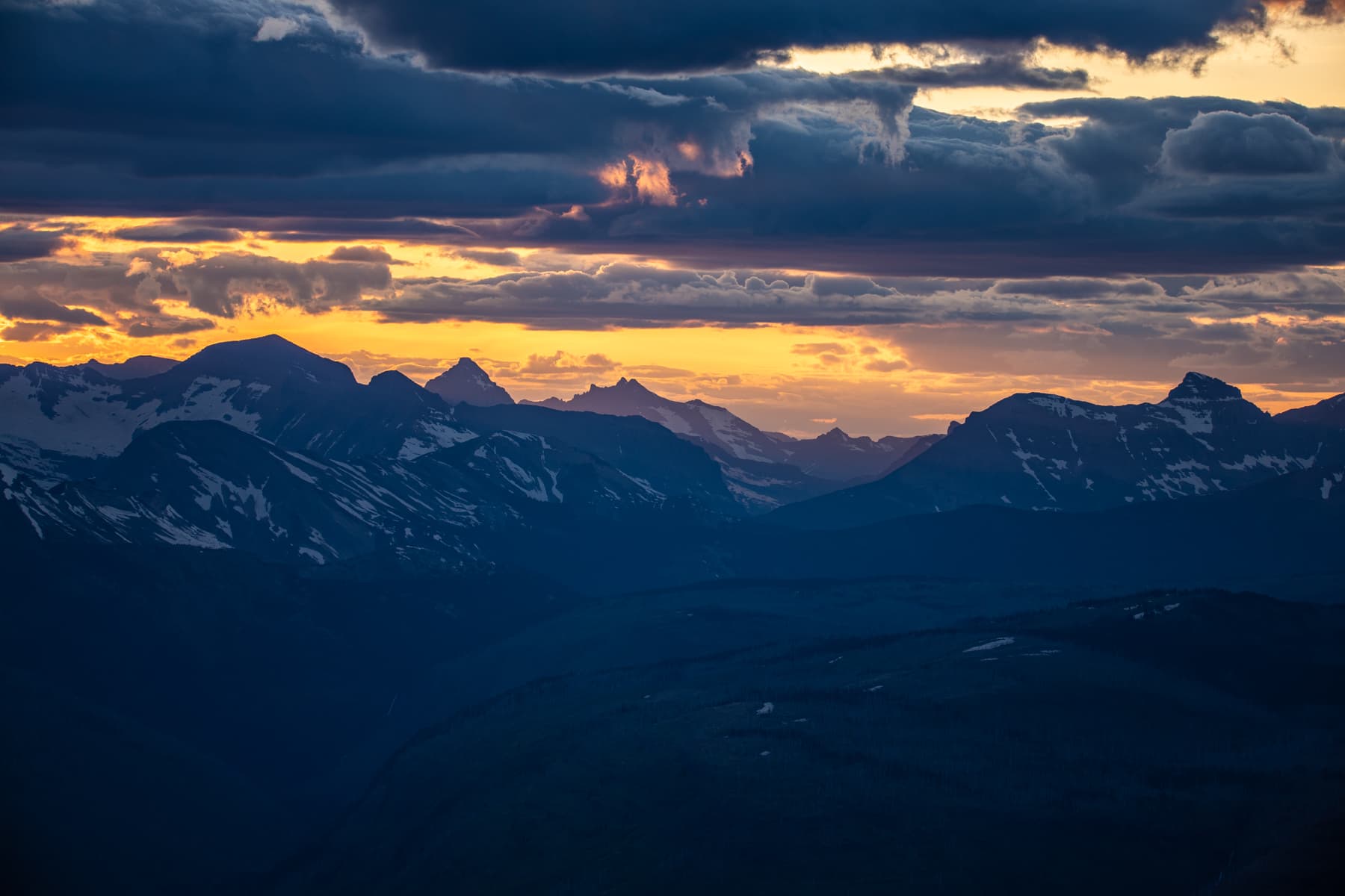 Blue mountains and a golden sunset with clouds