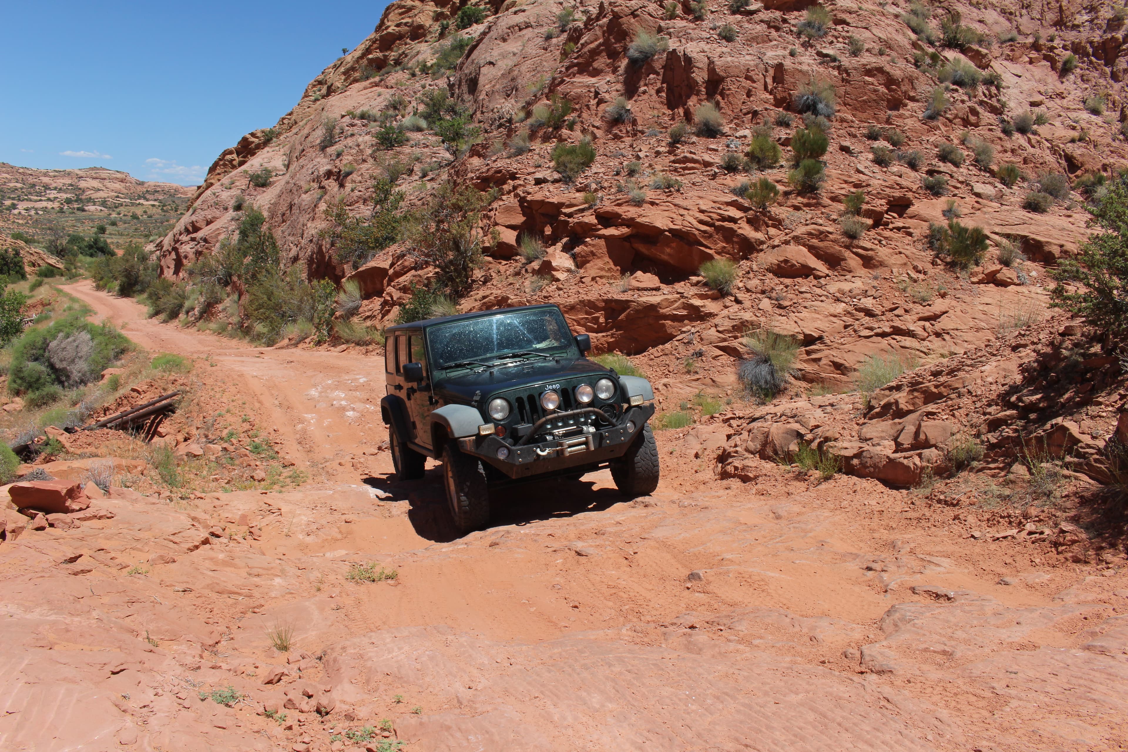 A jeep on a dirt road in a sandstone canyon