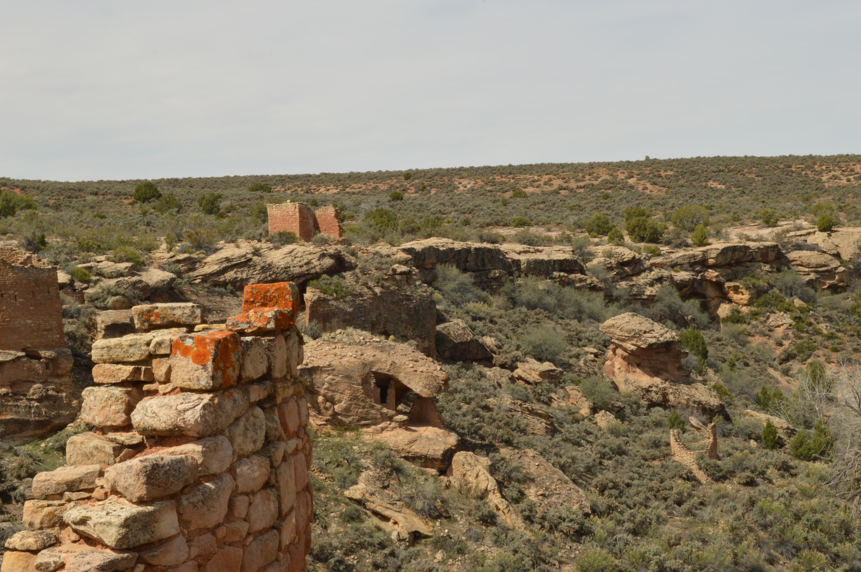 a crumbling stone wall in the foreground, with other stone structures across the canyon.