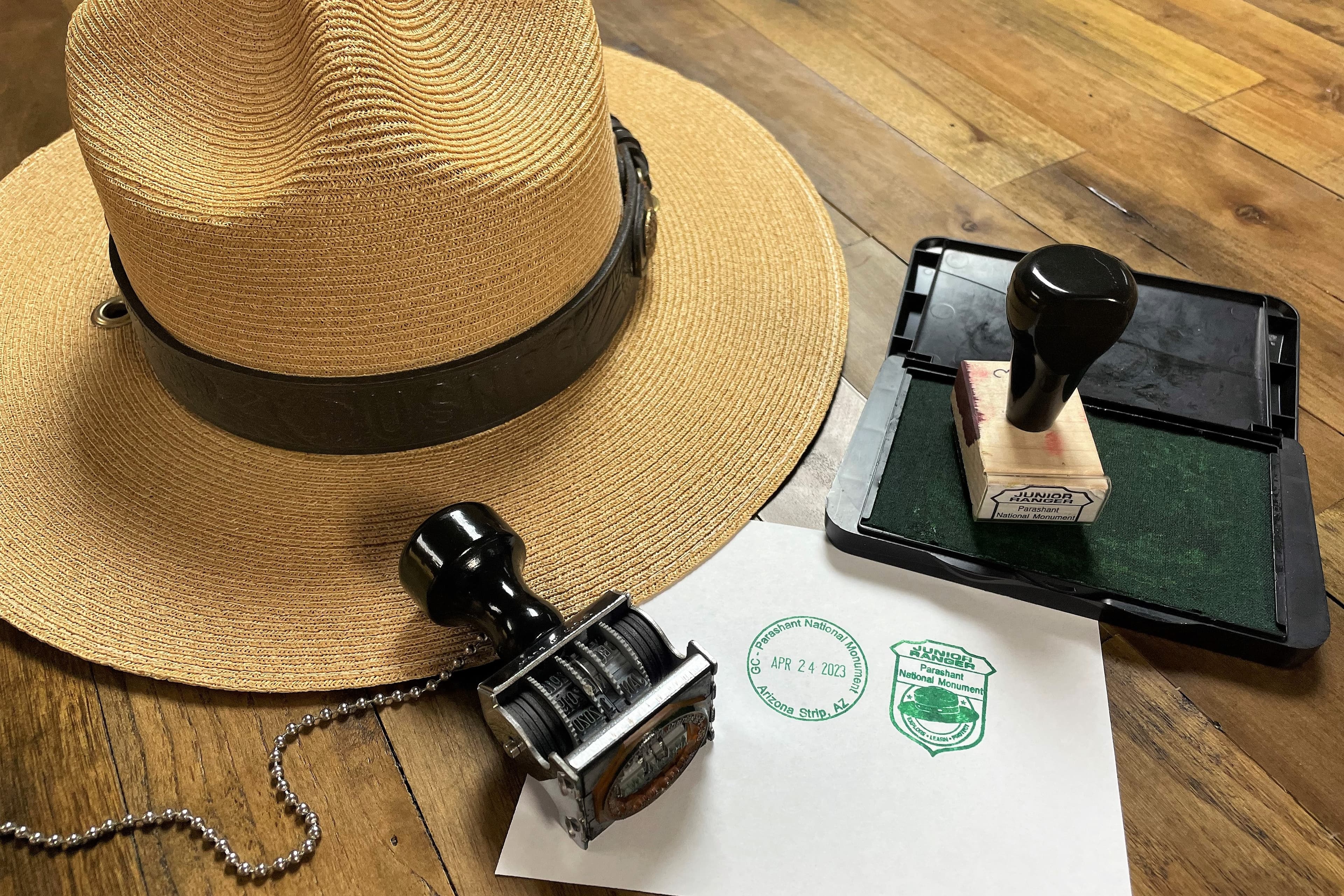 Image of a Park Ranger flat hat with the NPS Passport cancellation stamp and Junior Ranger stamp.