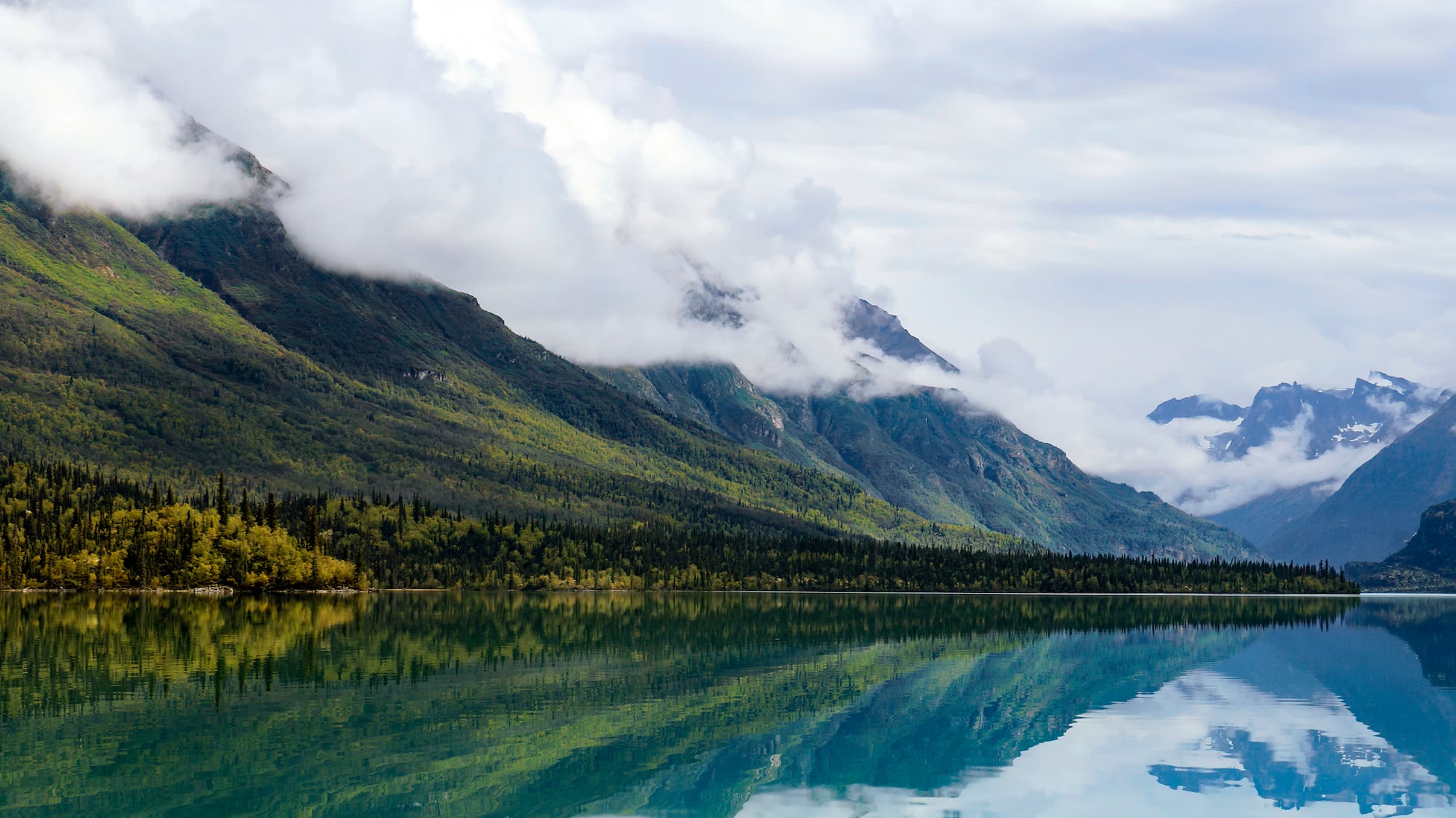 Mountains and yellow trees reflect in blue waters