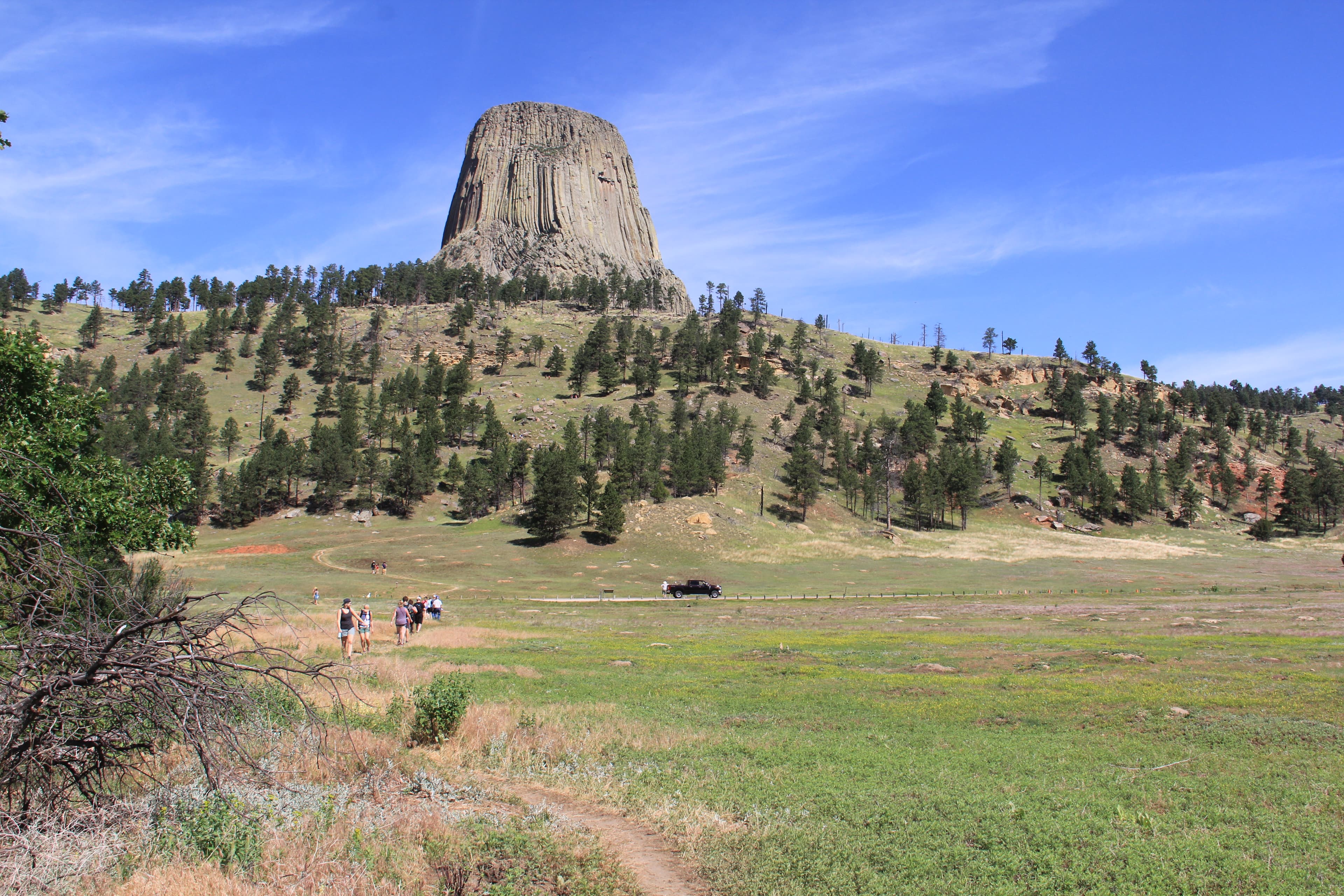 people walking along a dirt path through the prairie dog town, Devils Tower in the background