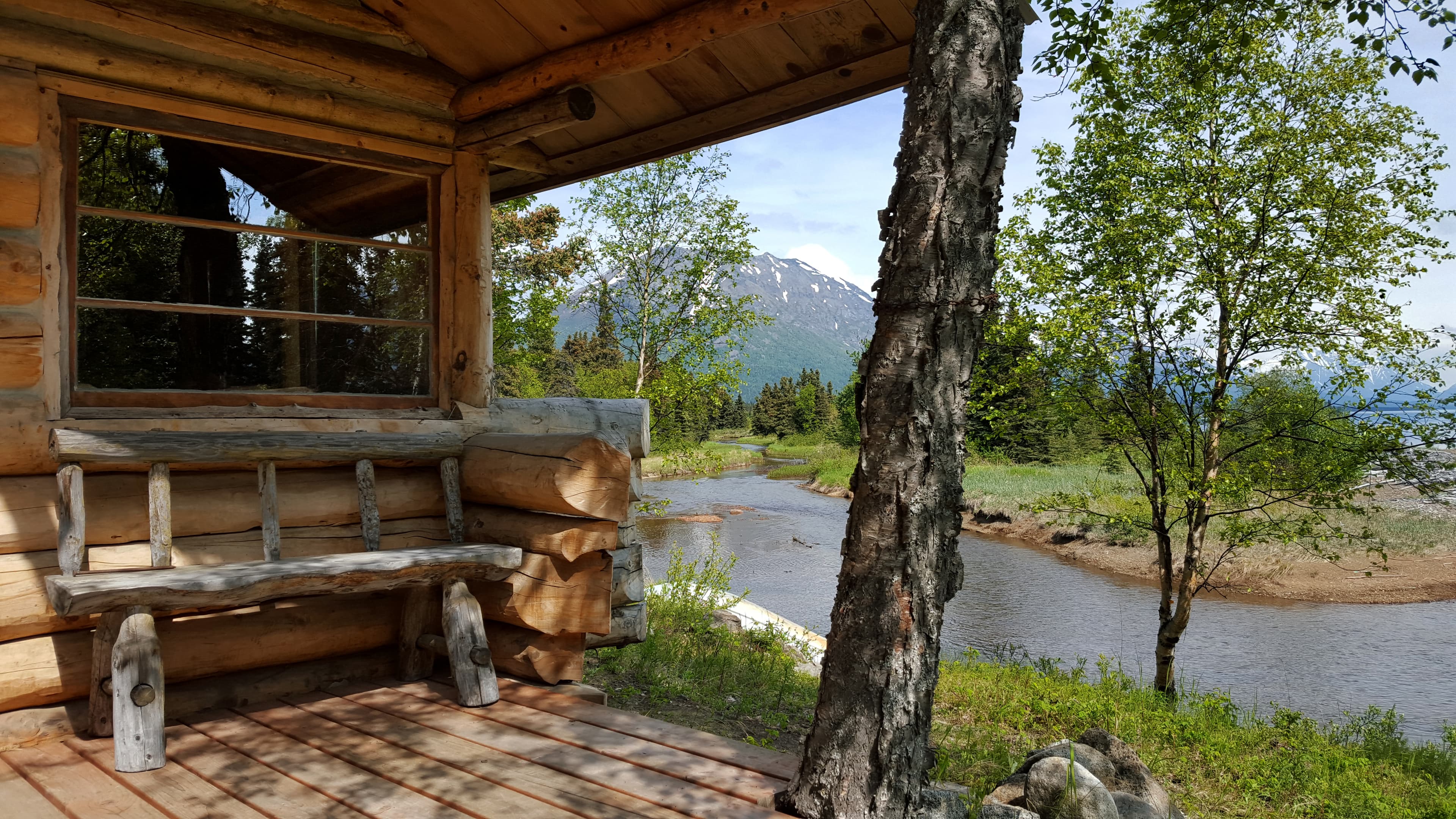 A wooden bench sits on the front porch of a cabin