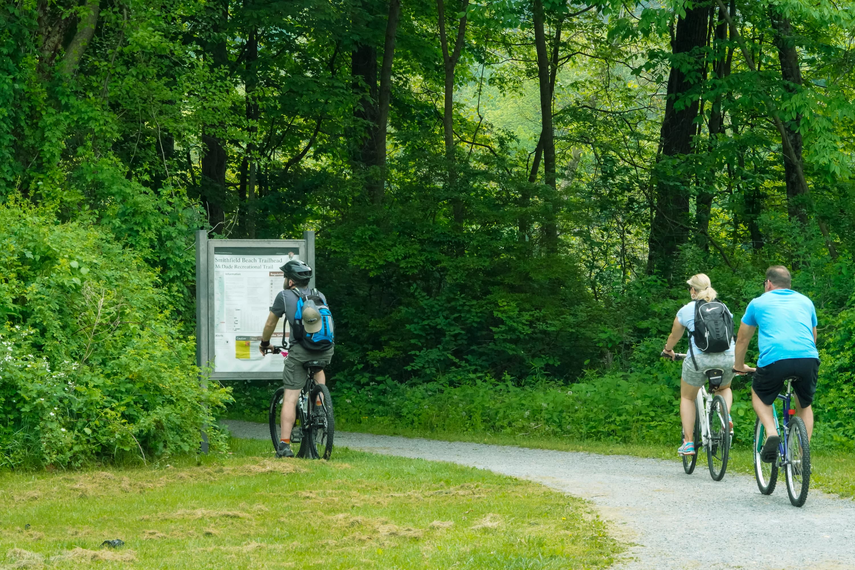 Three people bike onto the McDade Recreational Trail.