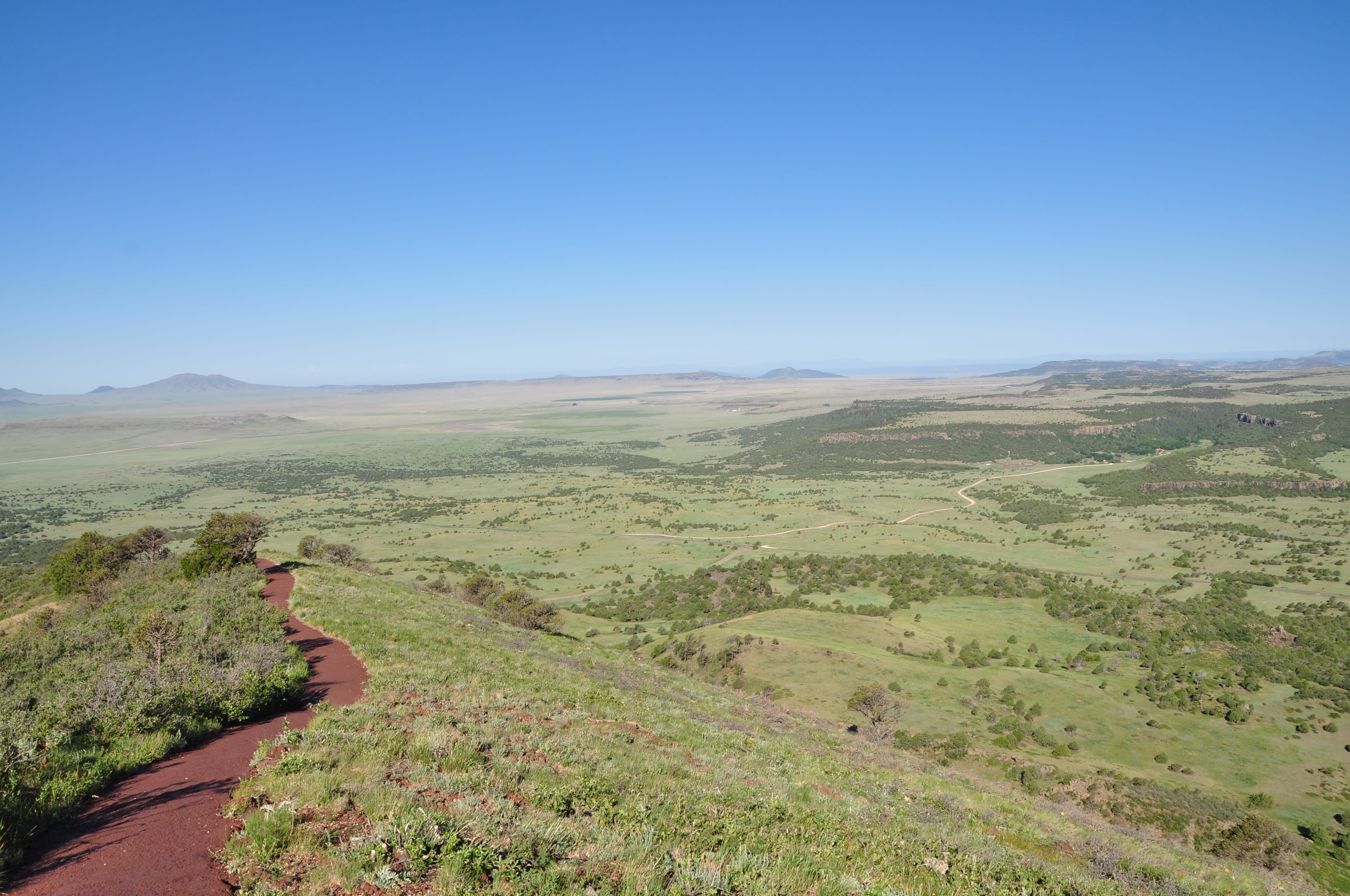 View of the Rim Trail to the left and the prairie and other volcanoes in the distance from the top