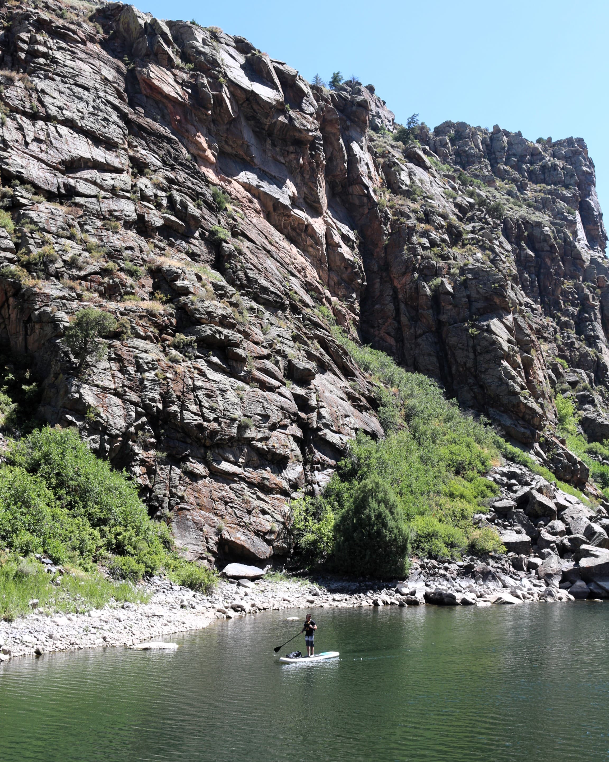 A person standup paddleboarding on a reservoir between steep cliff walls