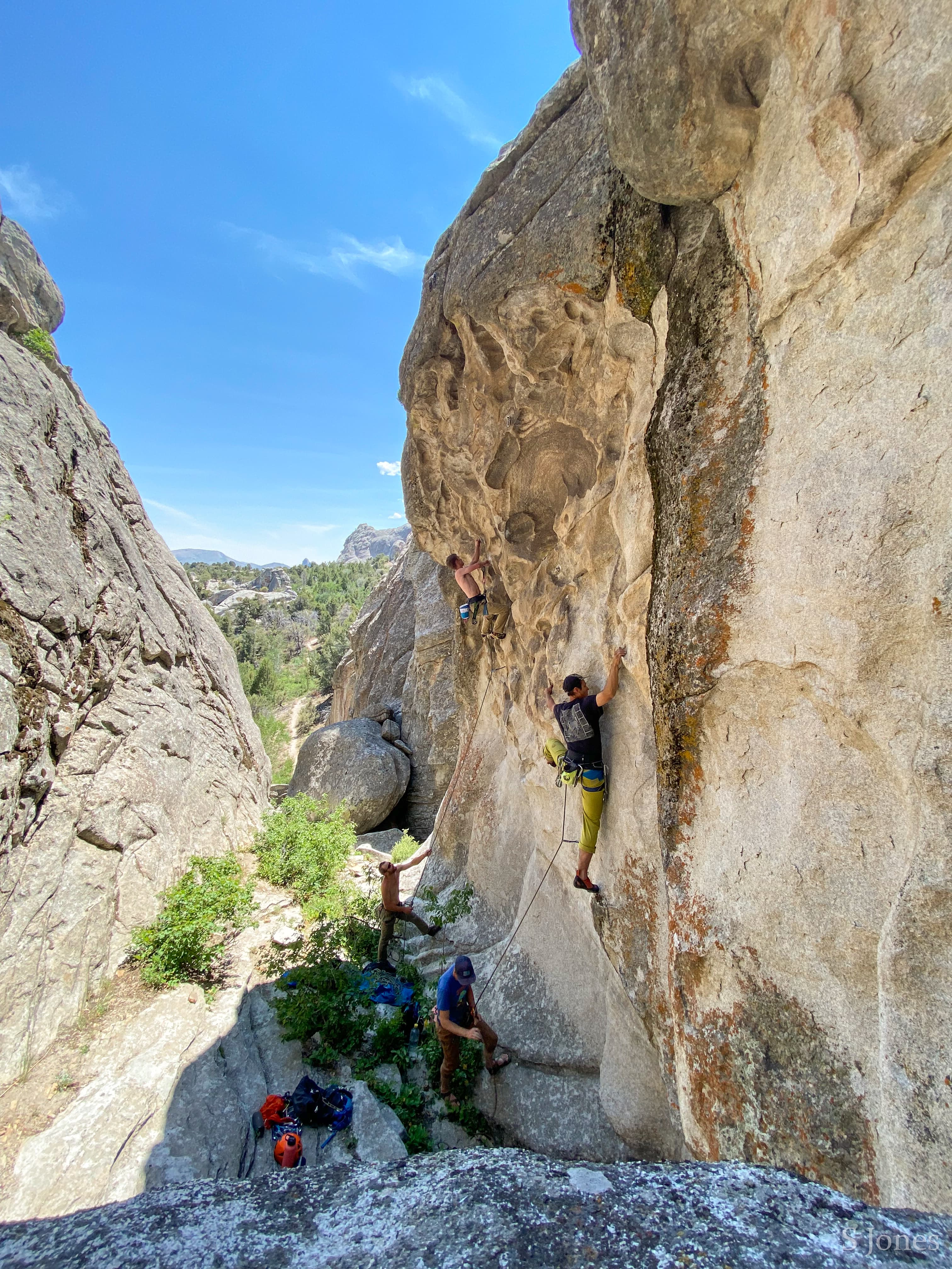Two climbers ascend neighboring routes in a scenic granite ravine.