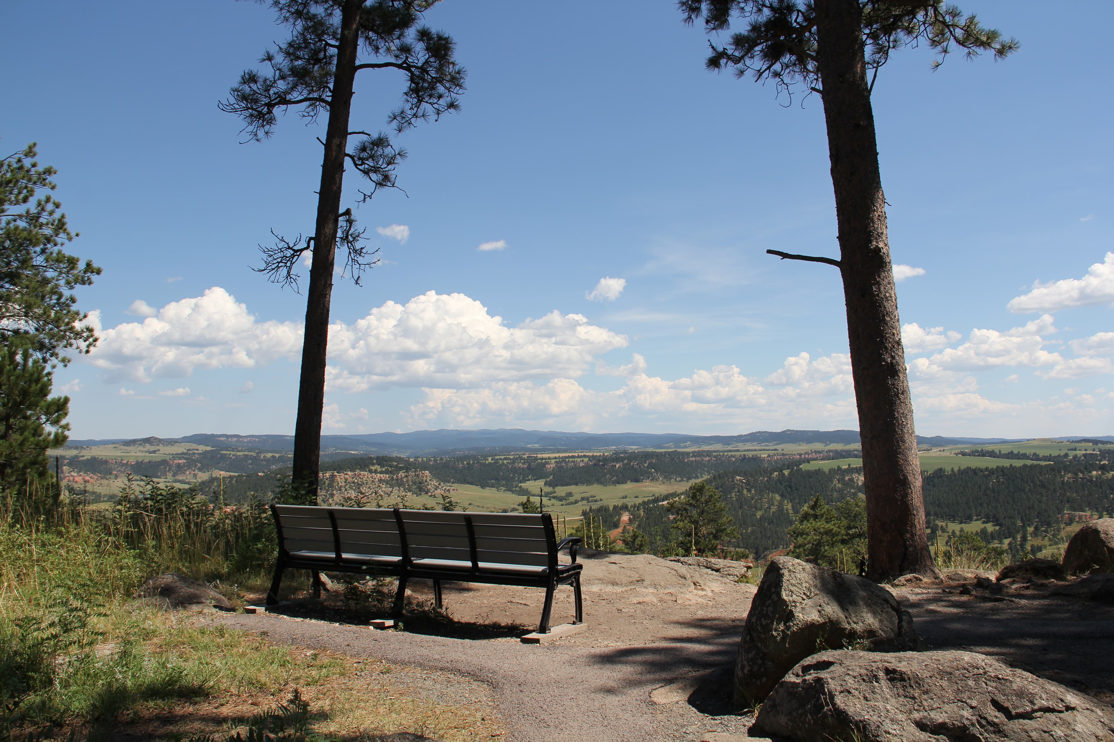 A bench along a trail overlooking a valley.