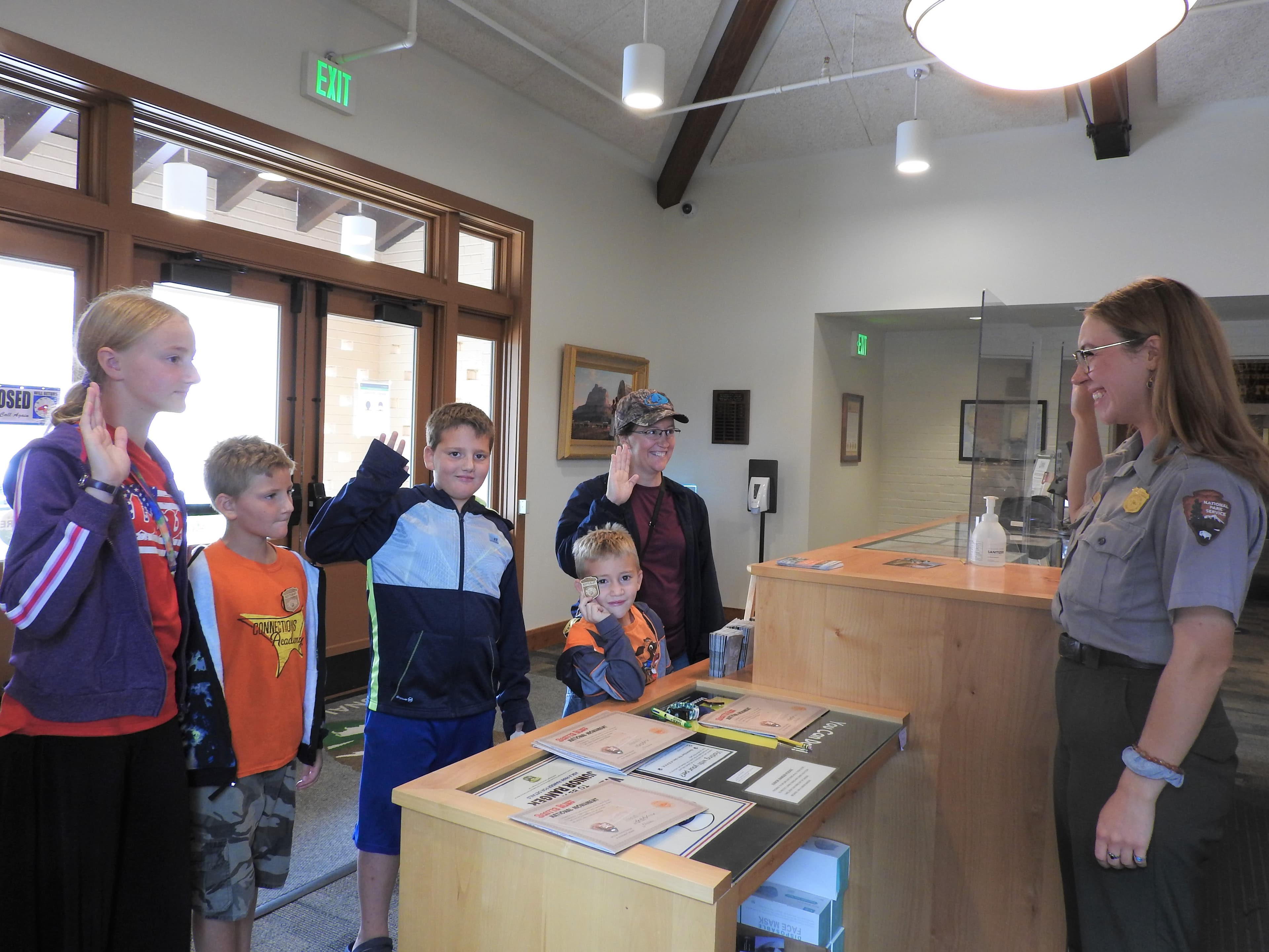 Five junior rangers raise their right hands and take the Junior Ranger Pledge with a NPS Ranger.