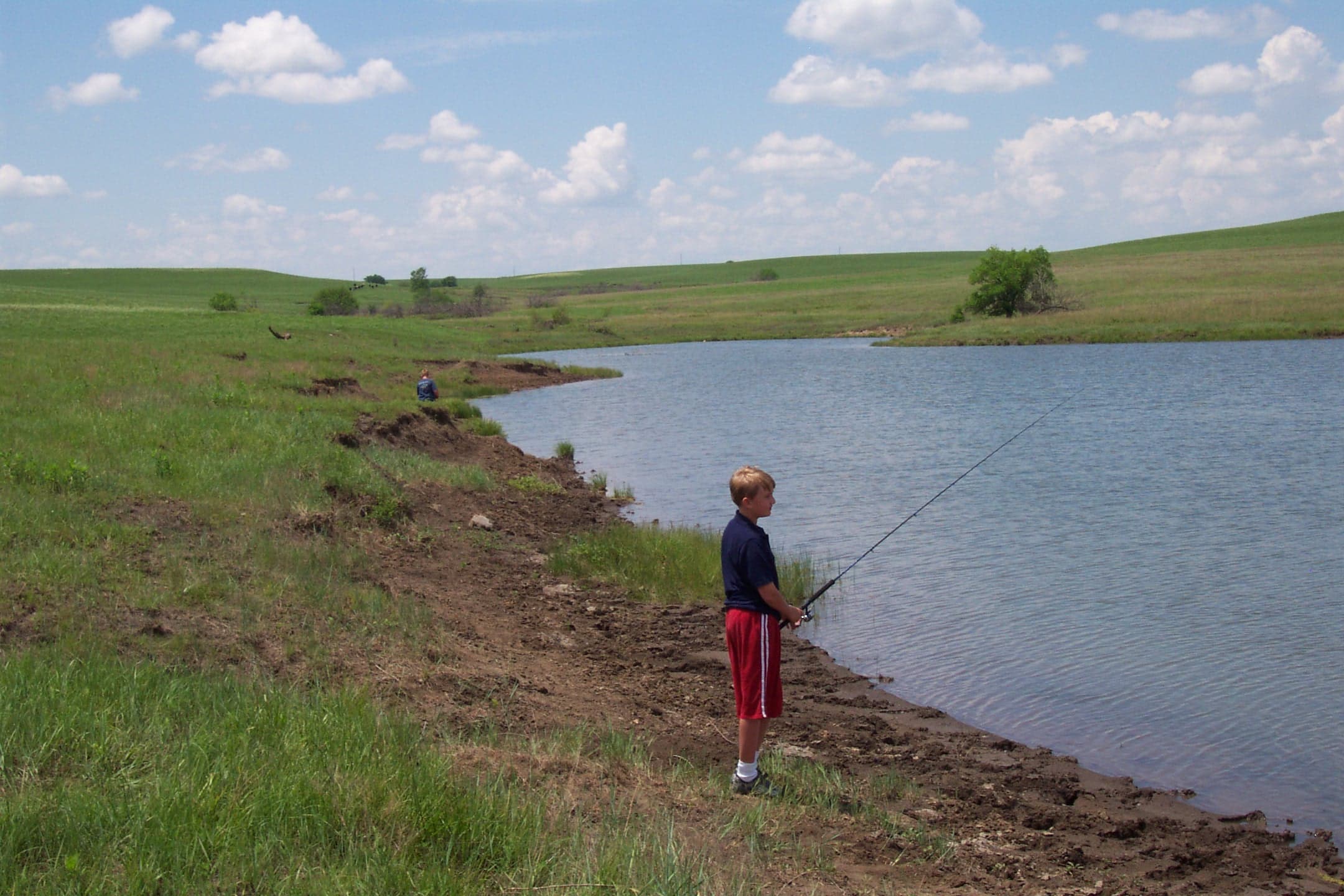 child with fishing pole by pond