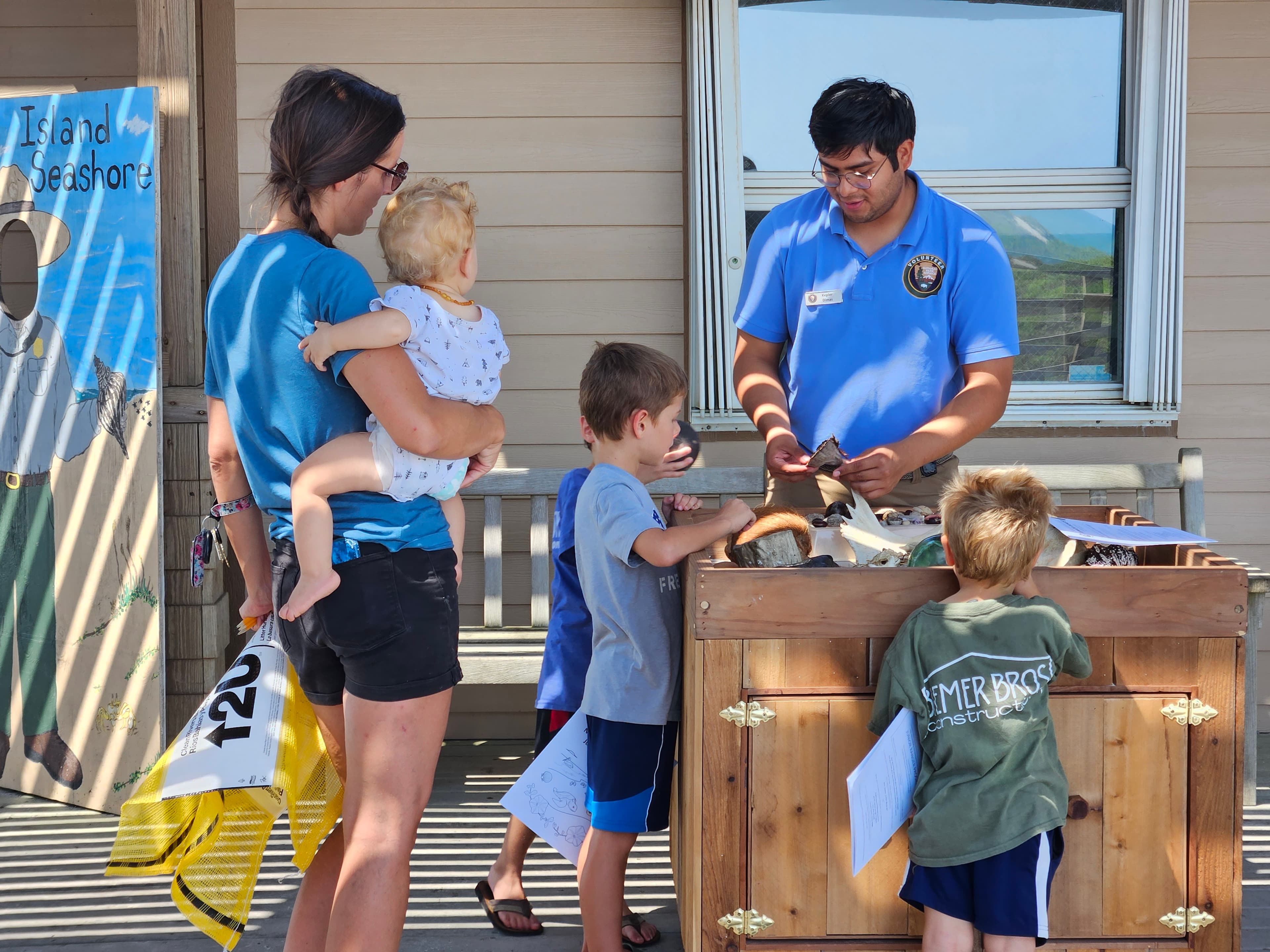 A park volunteer talks with a family about seashells.