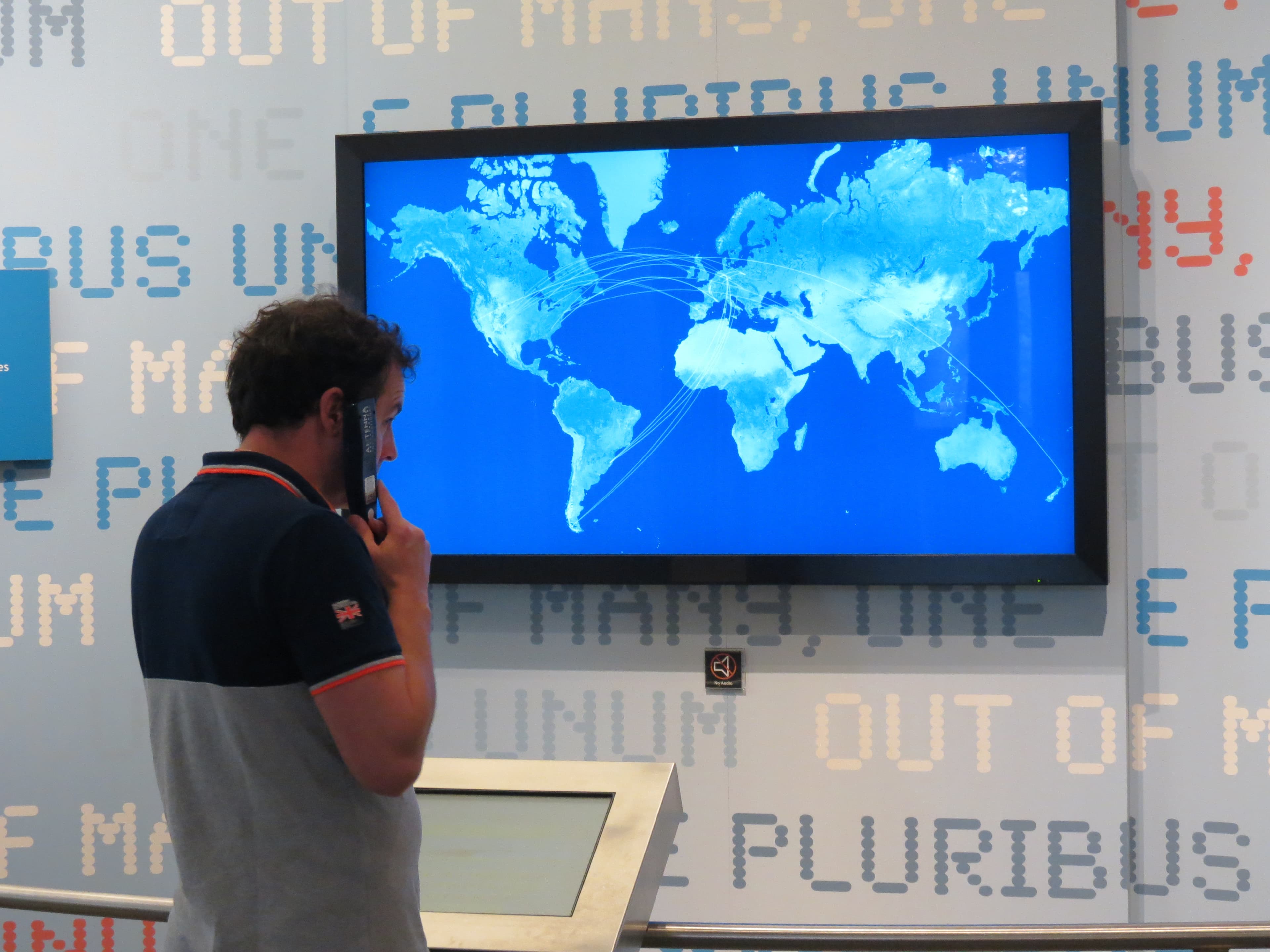 Man listening to audio tour while watching a display panel of the continents.