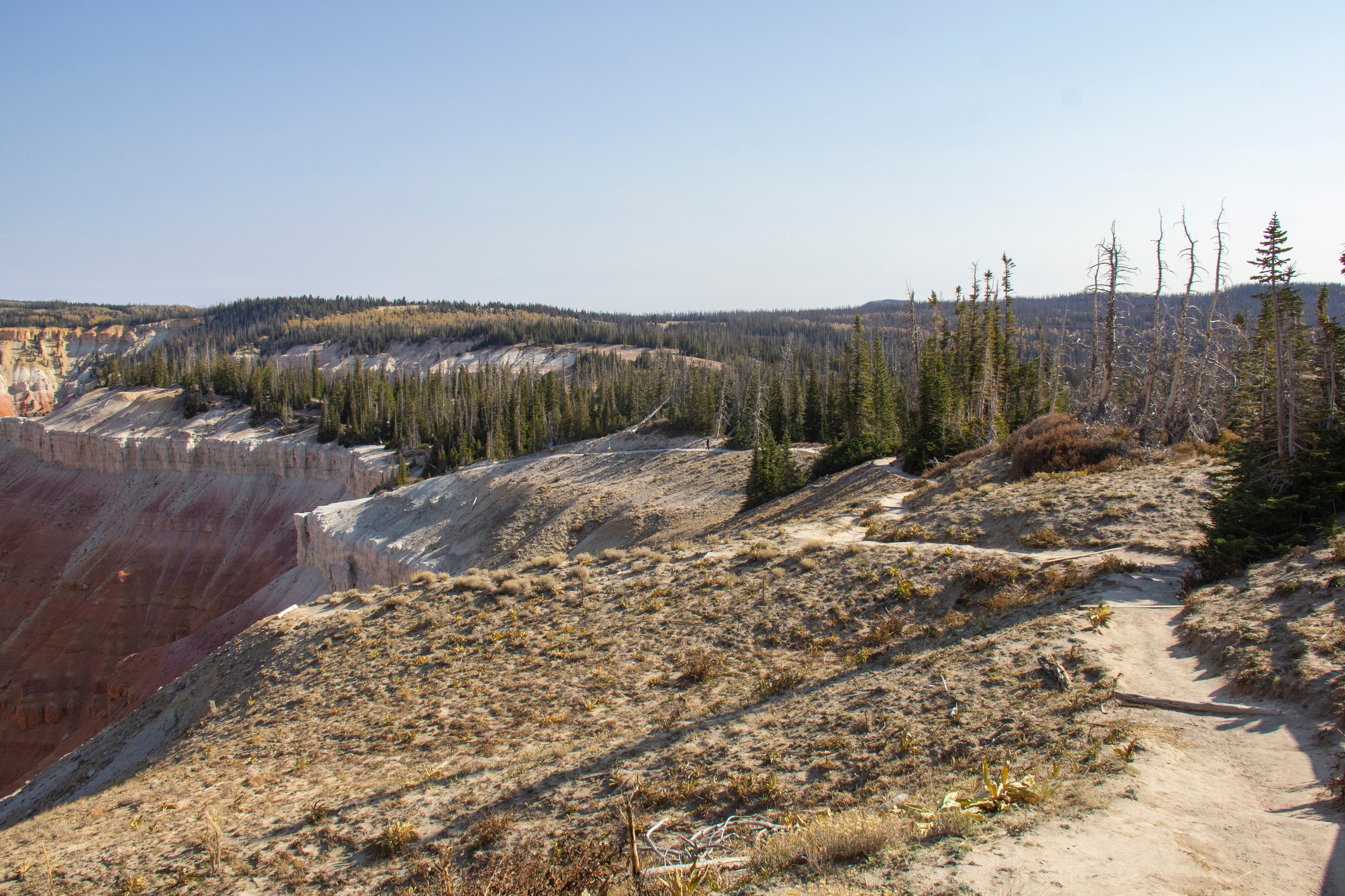 A dirt trail winds along the rim of a geologic amphitheater to the left.