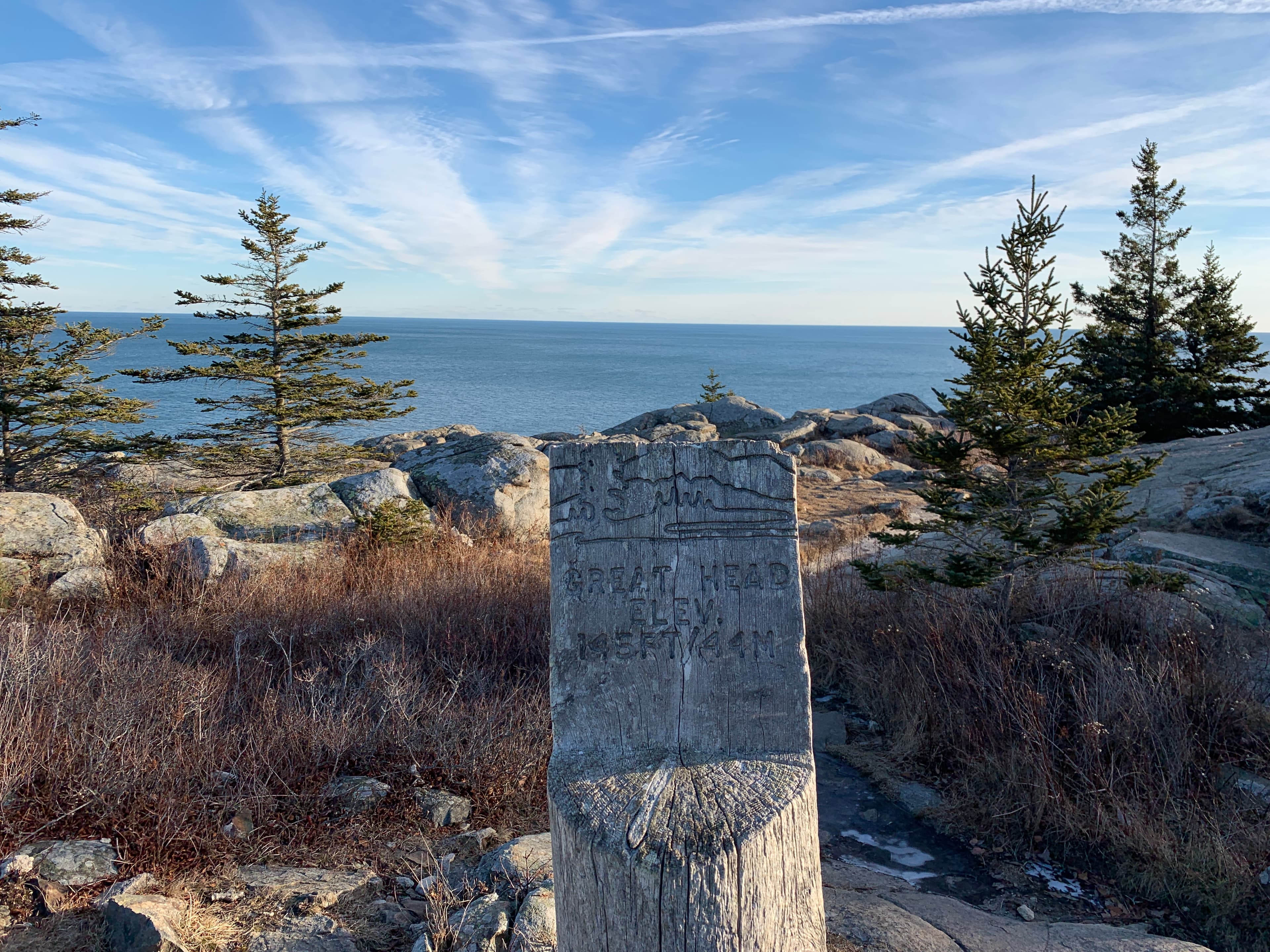 a wooden sign with in front of ocean view and trees