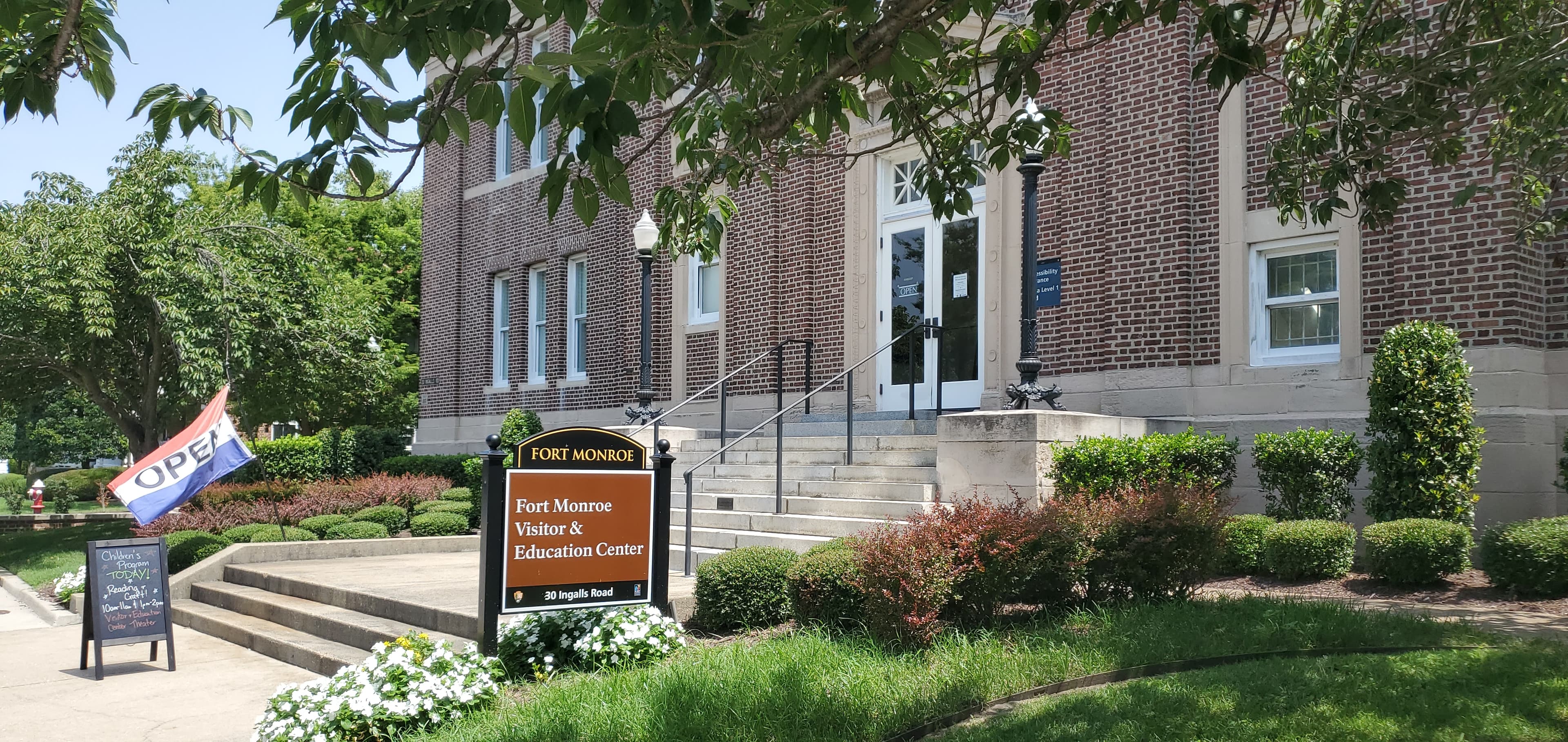 Signs in front of a brick Beaux-Arts style building state that the visitor center is open.