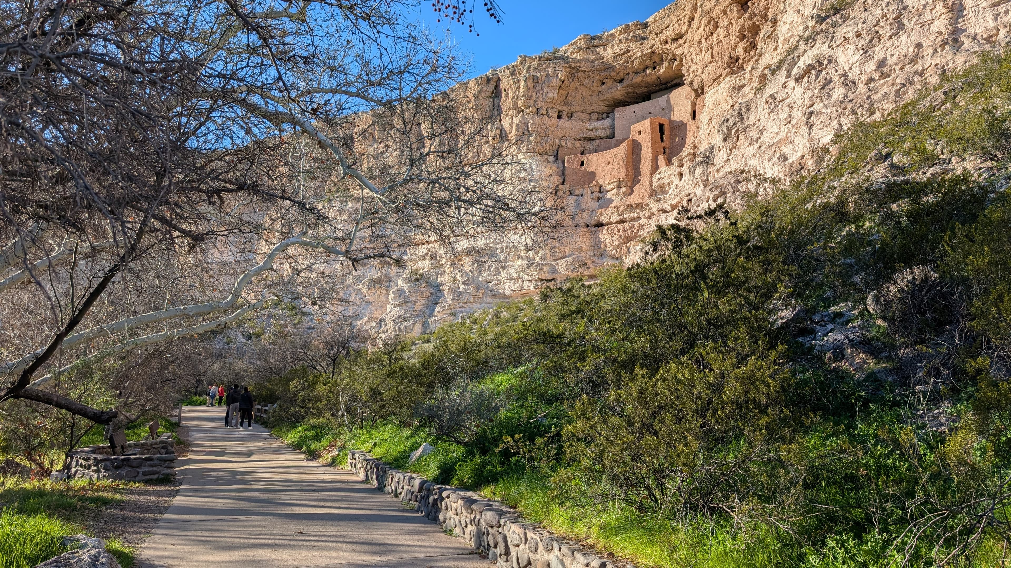 a large, multi-story adobe dwelling inside a large alcove on the side of a cliff