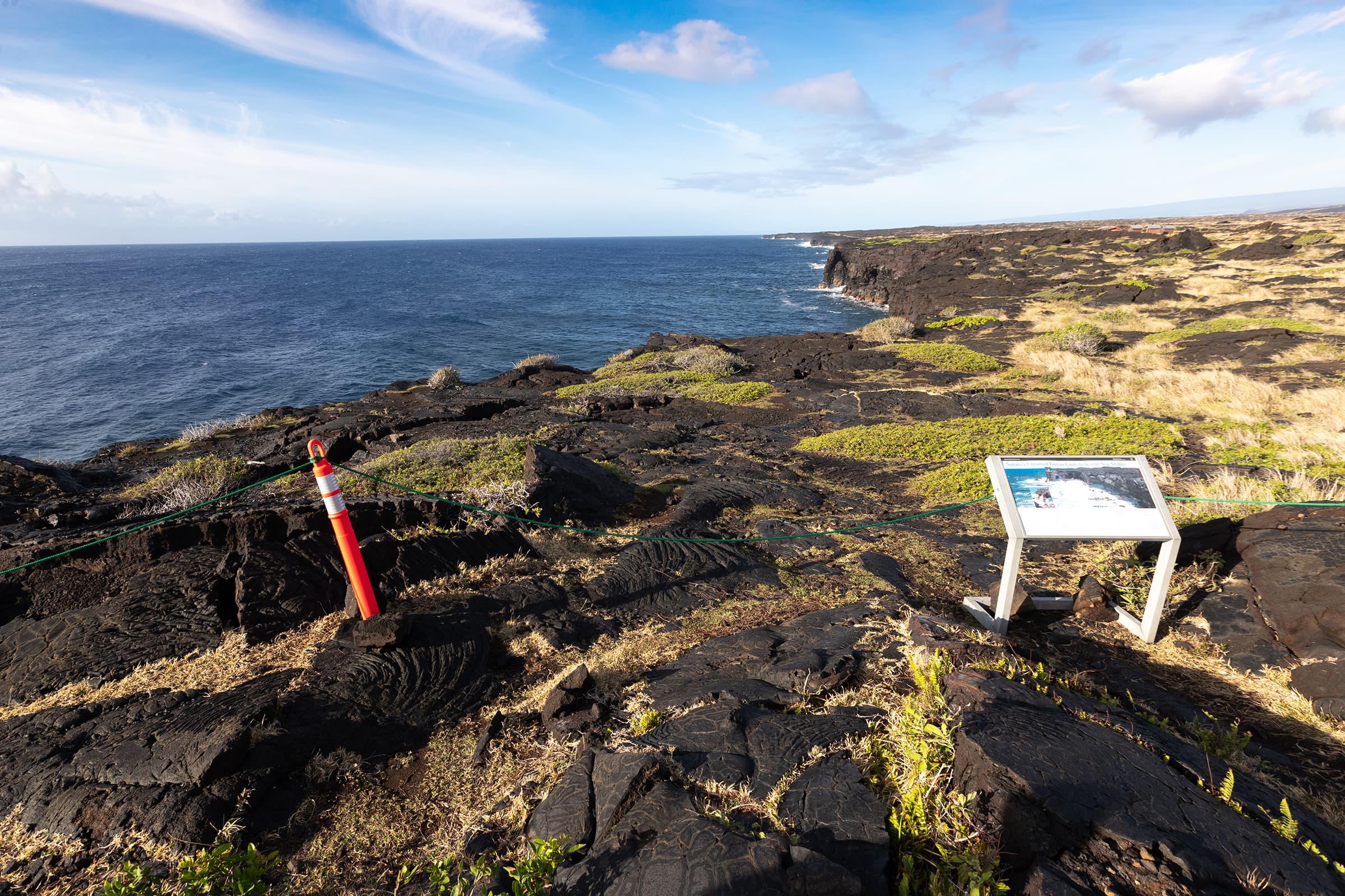 A viewpoint of dramatic sea cliffs with a wayside exhibit in the foreground