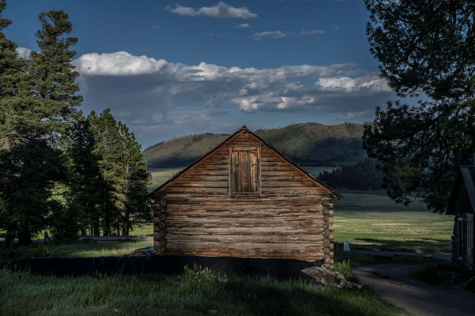 A historic log building overlooking a montane grassland.