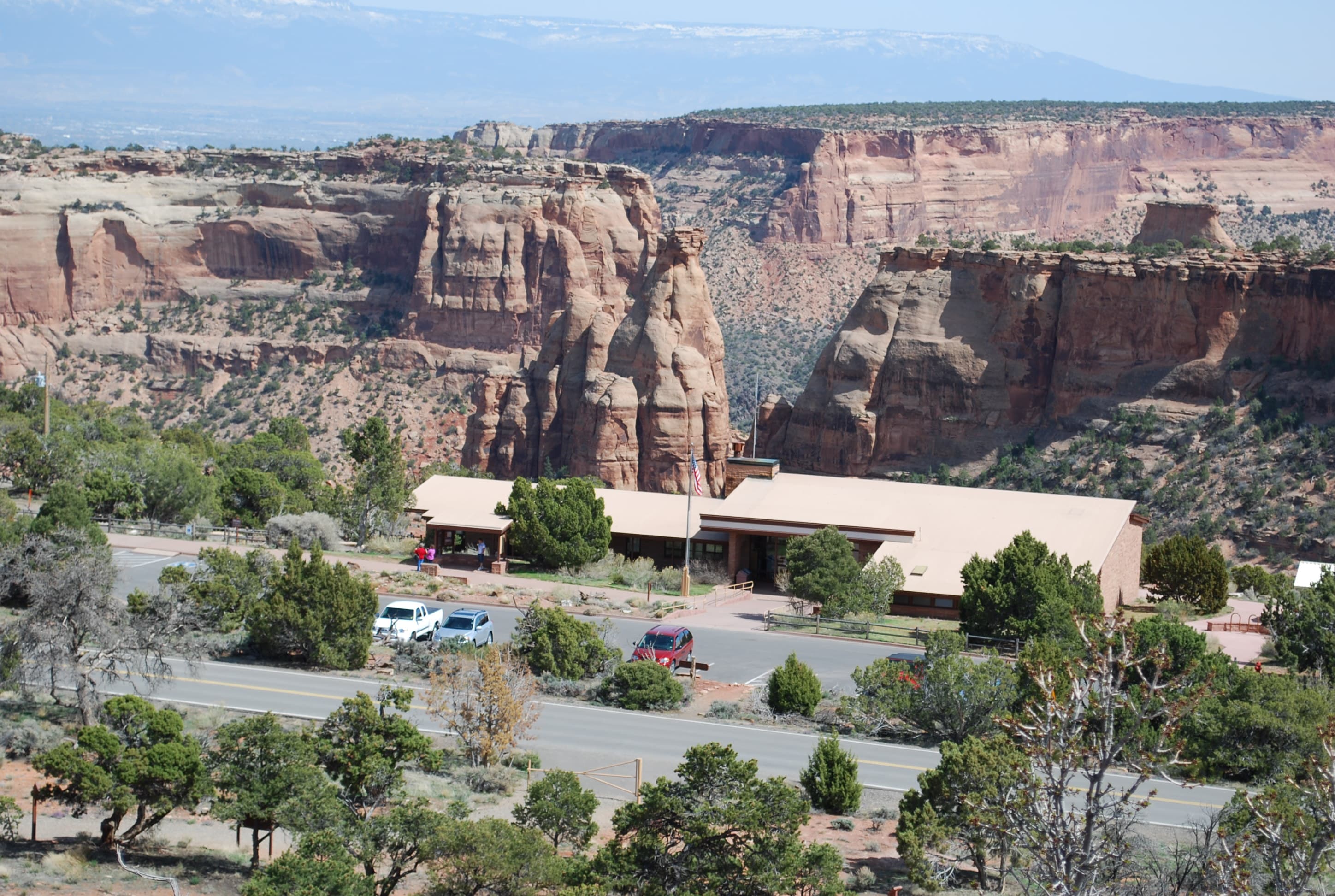 low, flat brown building surrounded by trees and parking lot, backdrop of steep canyon walls