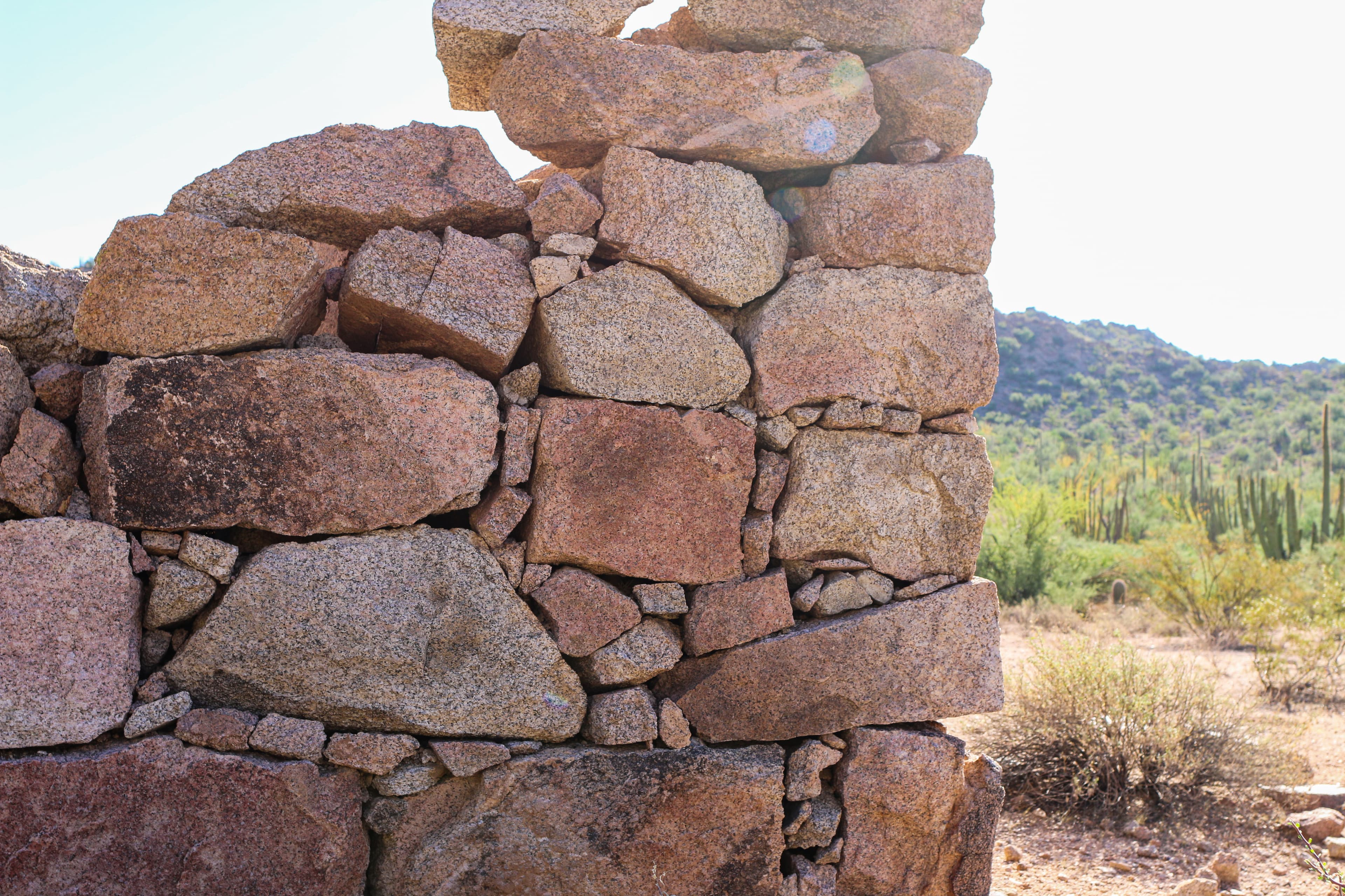 The corner of a historic, dilapidated stone building, constructed of local granite.