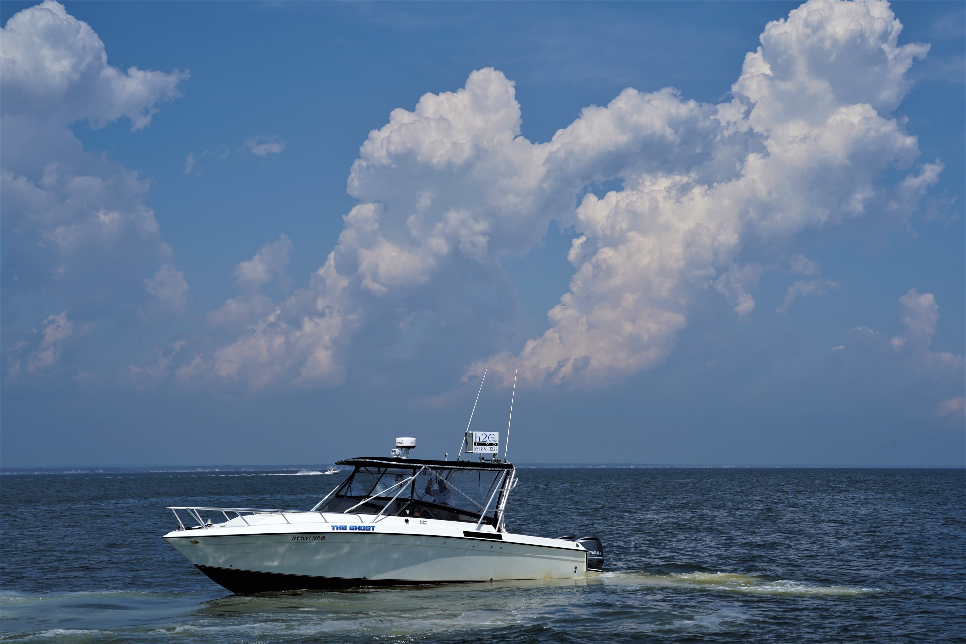 A mid sized boat floats before a dramatic cloud-filled sky.