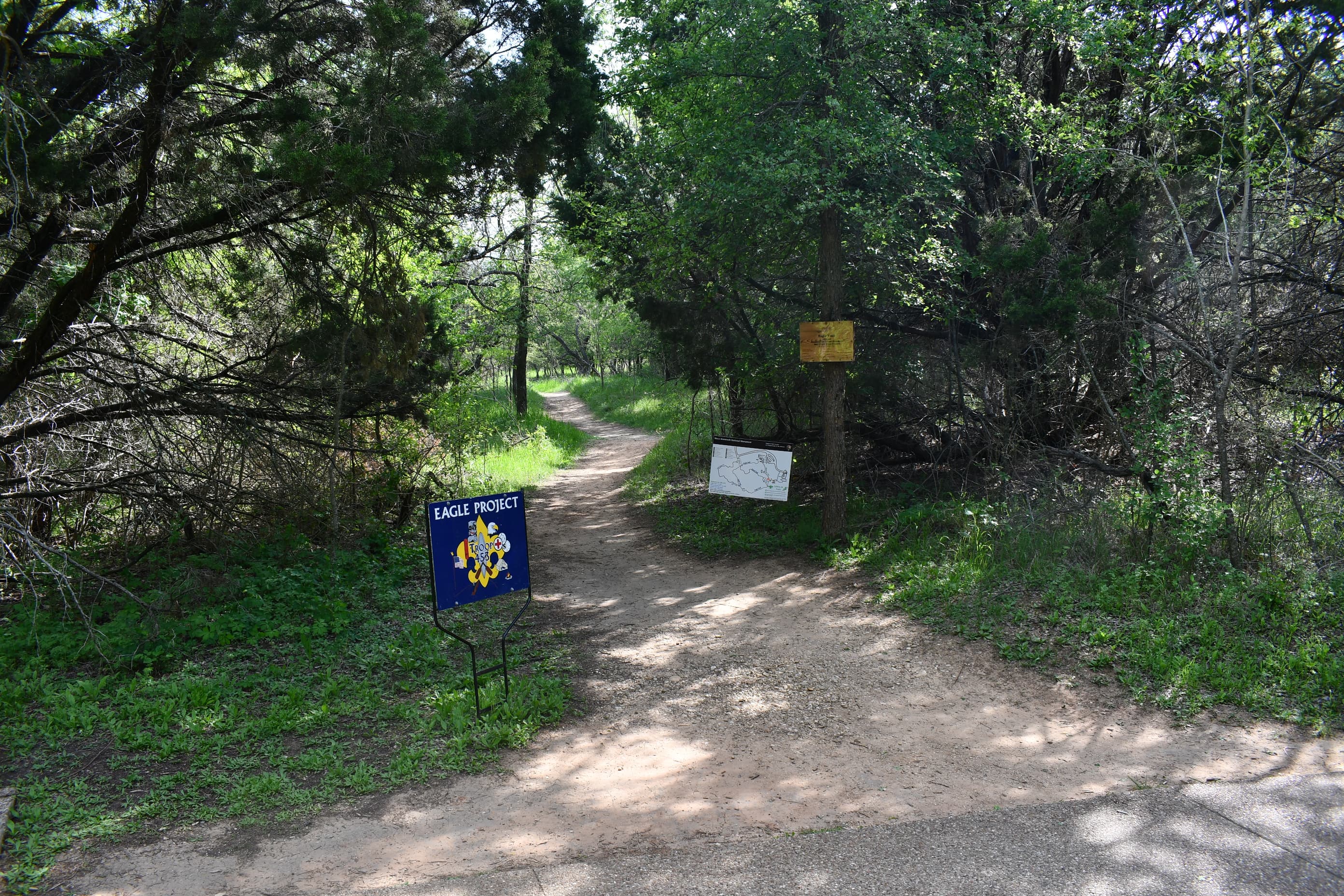 A sign with the Boy Scouts logo and the words "Eagle Project" stands at the start of a dirt trail.