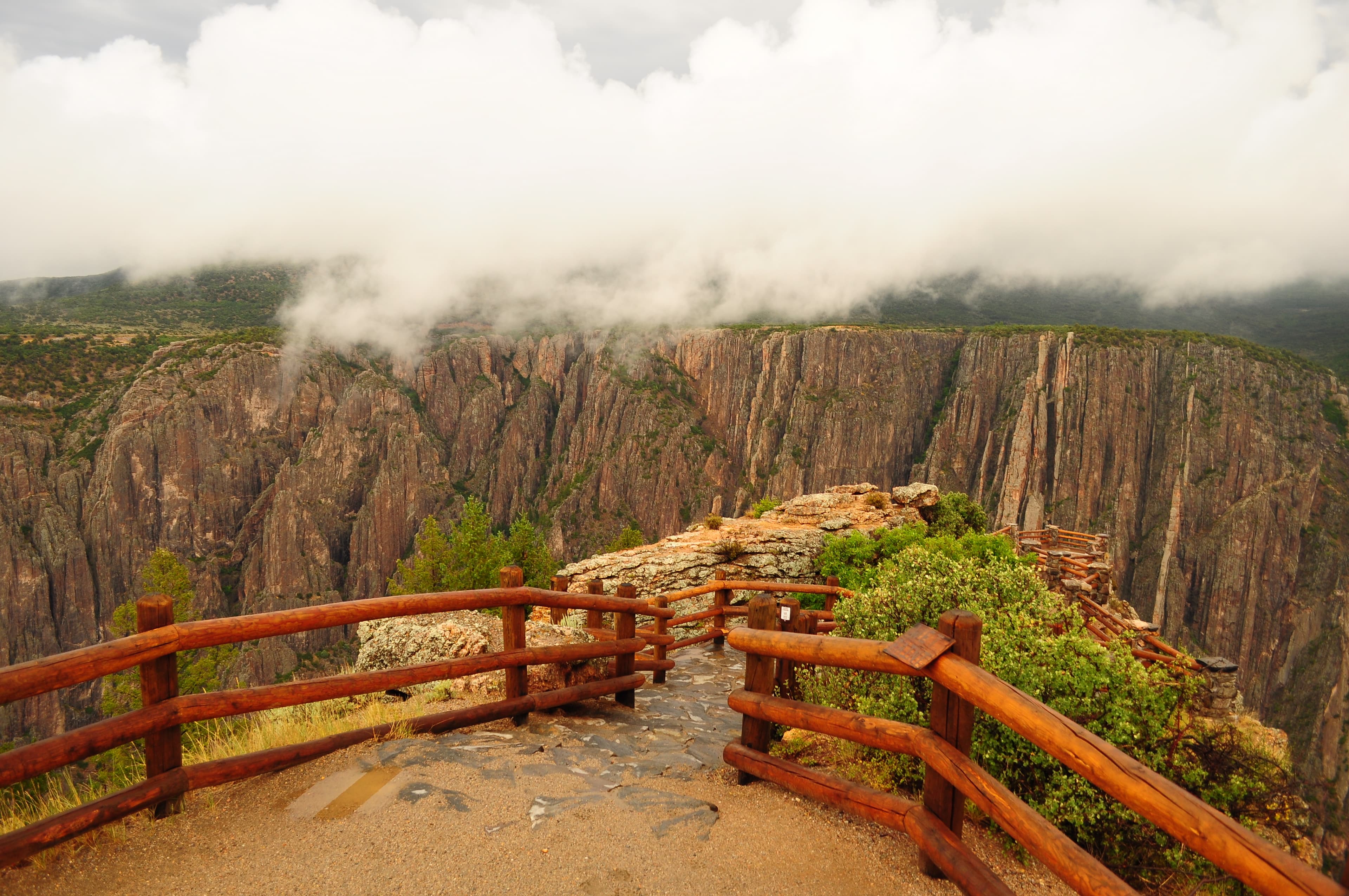 An overlook lined with wooden fencing leading towards a canyon edge