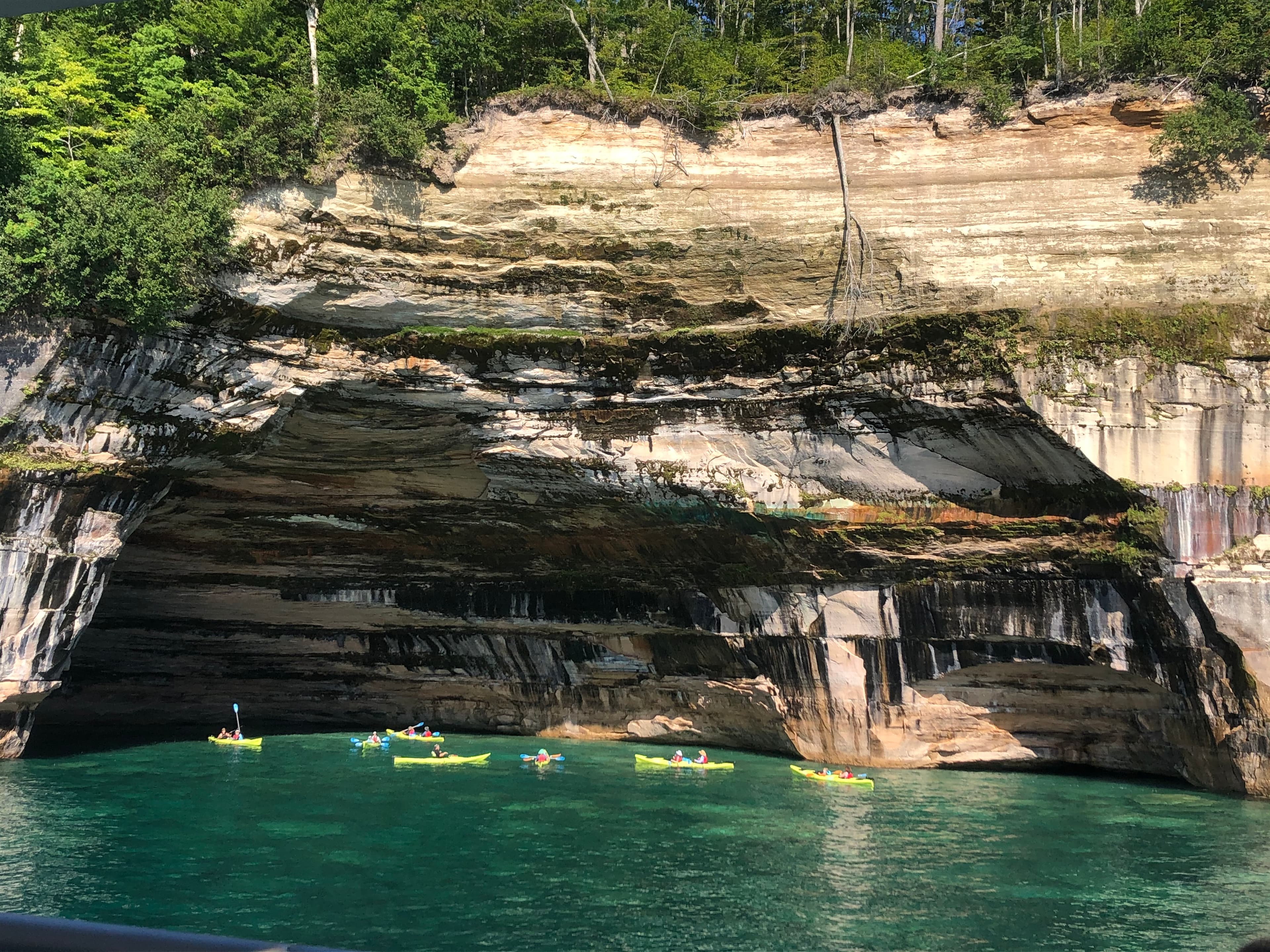 Group of yellow kayaks next to colorful cliff