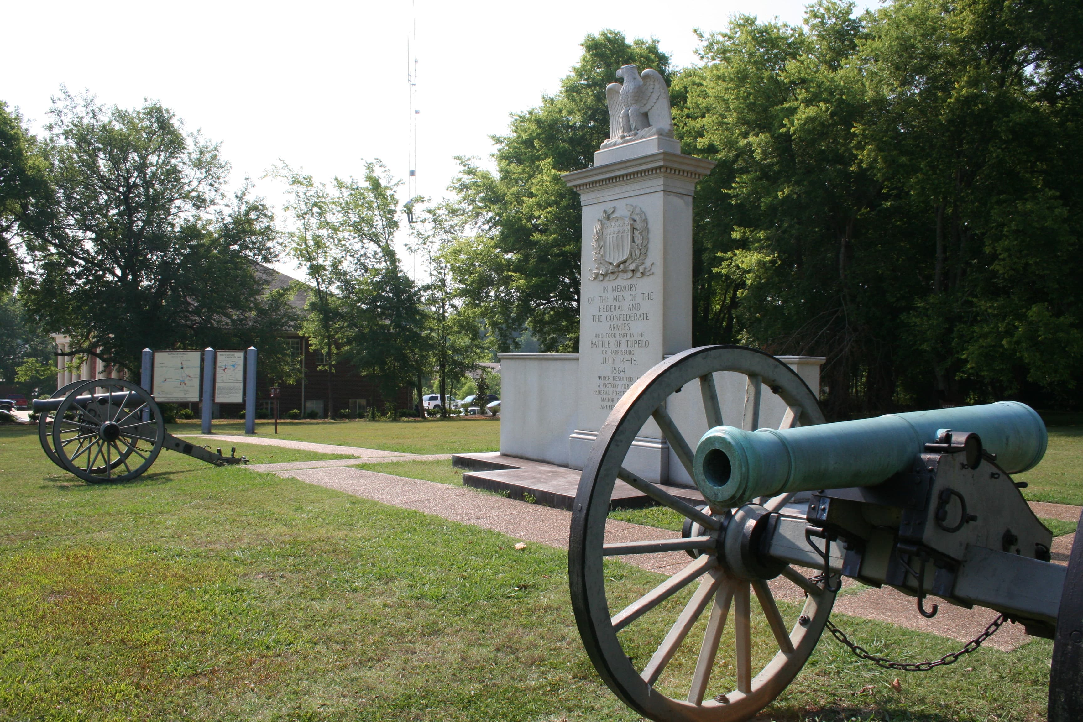 White granite monument with a carved eagle on top with 2 civil war cannons flanking monument