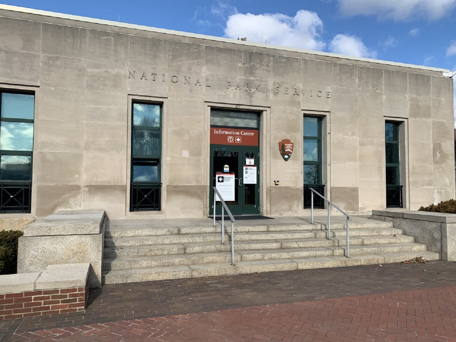 The Information Center on Liberty Island is a concrete building with a few steps leading up to it.