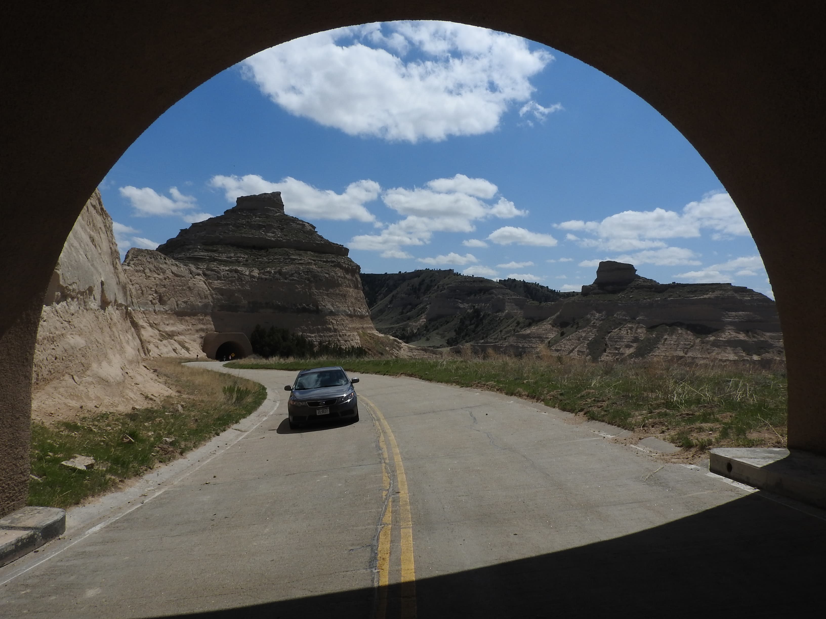 A car approaches a tunnel on a steep, winding road.