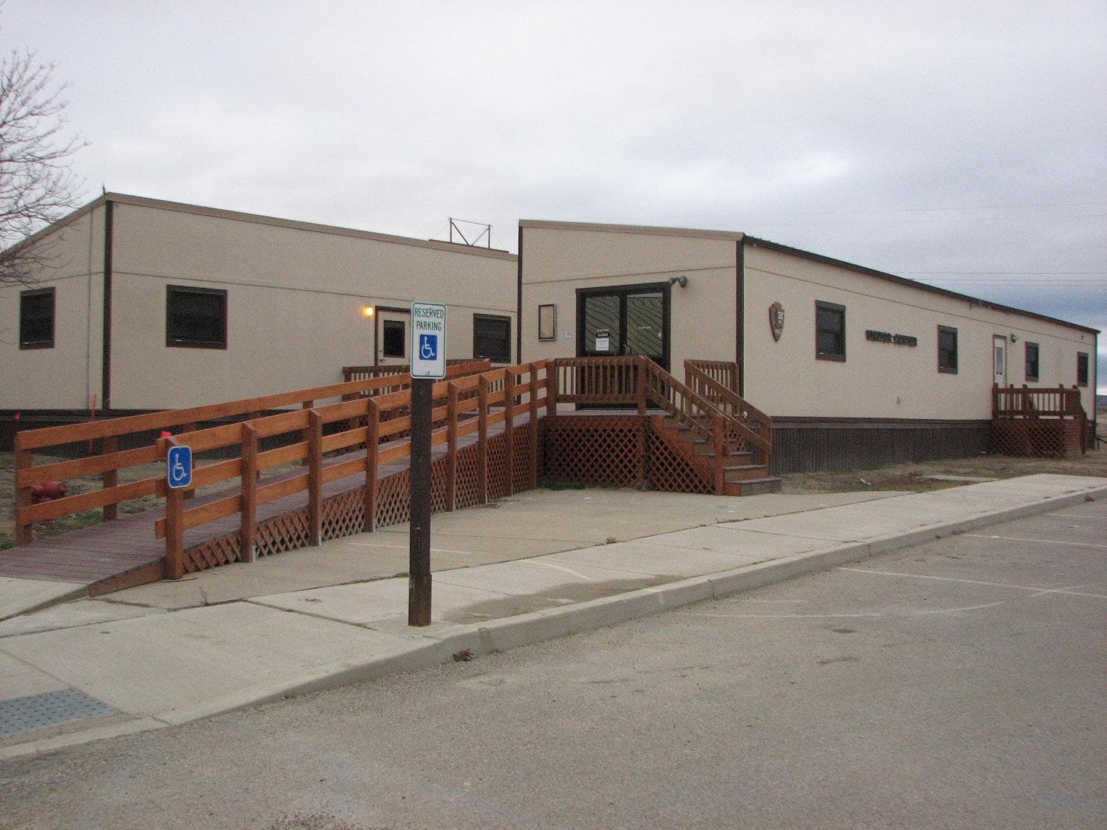 Two tan trailers with wood railed ramp leading to them.